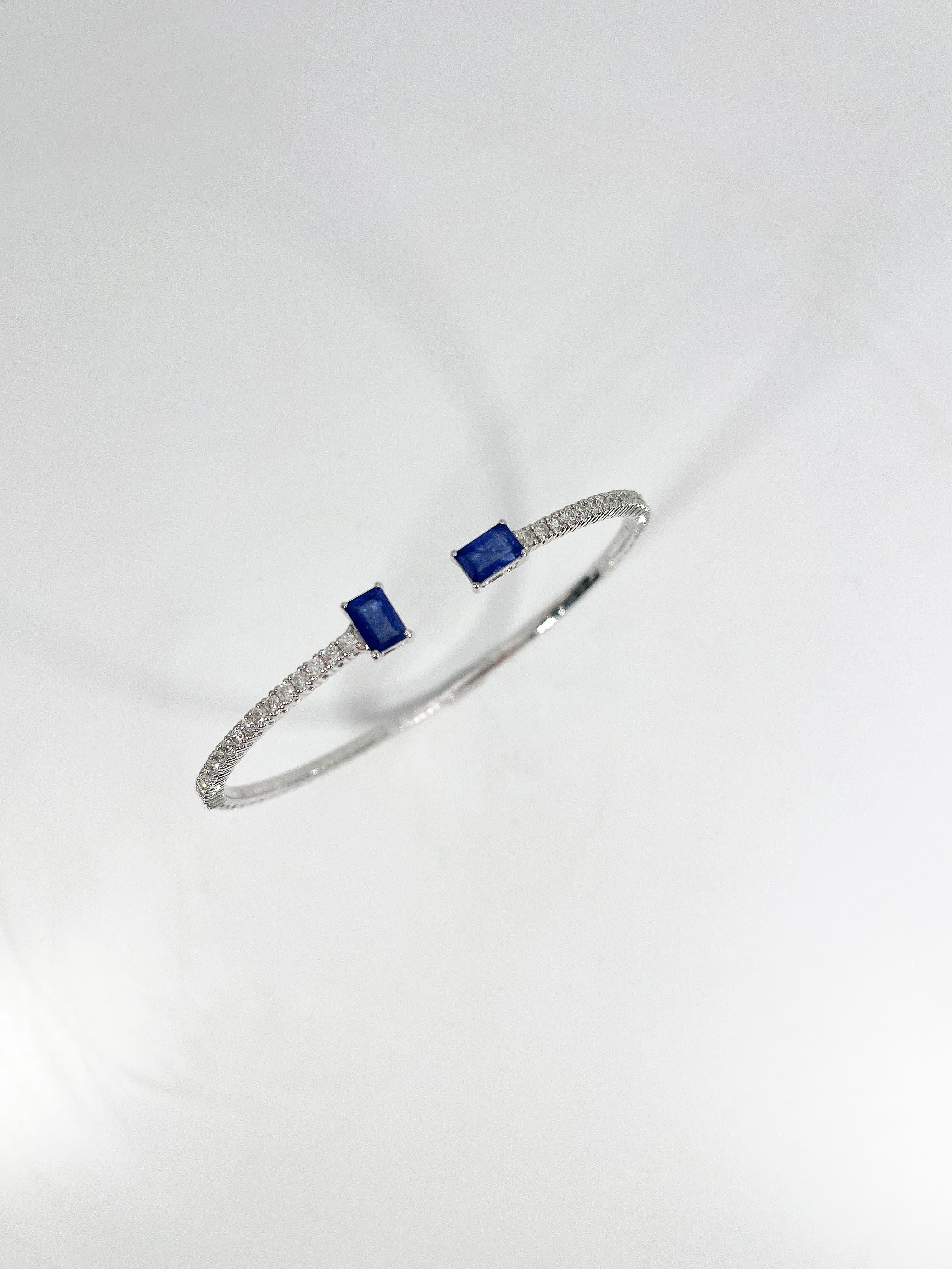 14k white gold diamond and sapphire flex bangle. The diamonds in this bracelet are all round, the two sapphires are both radiant cut, the bangle will stretch to fit almost any wrist, the width is 6 mm, and the total weight is 8.75 grams.