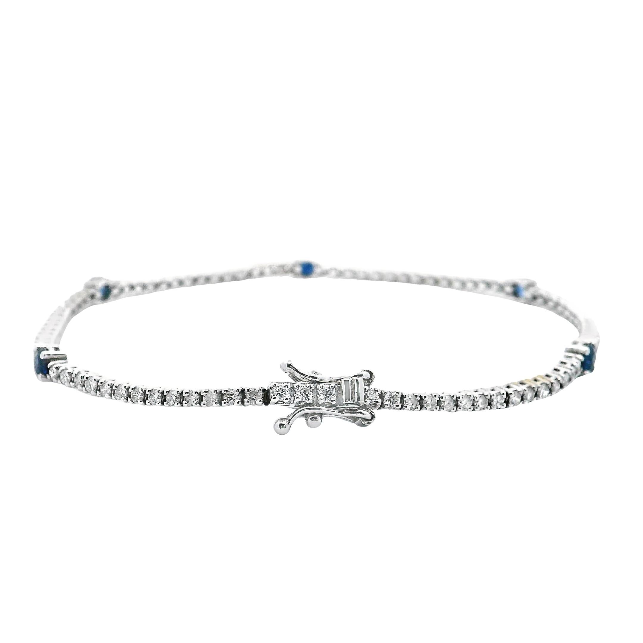 14K white gold tennis bracelet with 87 round brilliant-cut diamonds weighing 1.50 carats total and 5 round faceted blue sapphires 0.75 carats total.

- 7 inches long.
- Diamonds are H color, SI clarity.
- Double figure 8 safety clasp.