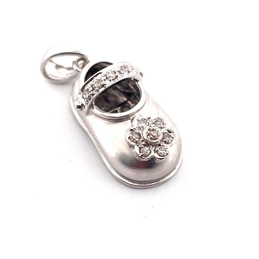 Adorn your necklace with this enchanting 14K white gold charm pendant in the shape of a baby shoe. The shoe is elegantly designed with a flower motif consisting of seven sparkling diamonds, the shoe belt is adorned with five diamonds. 

The chain is
