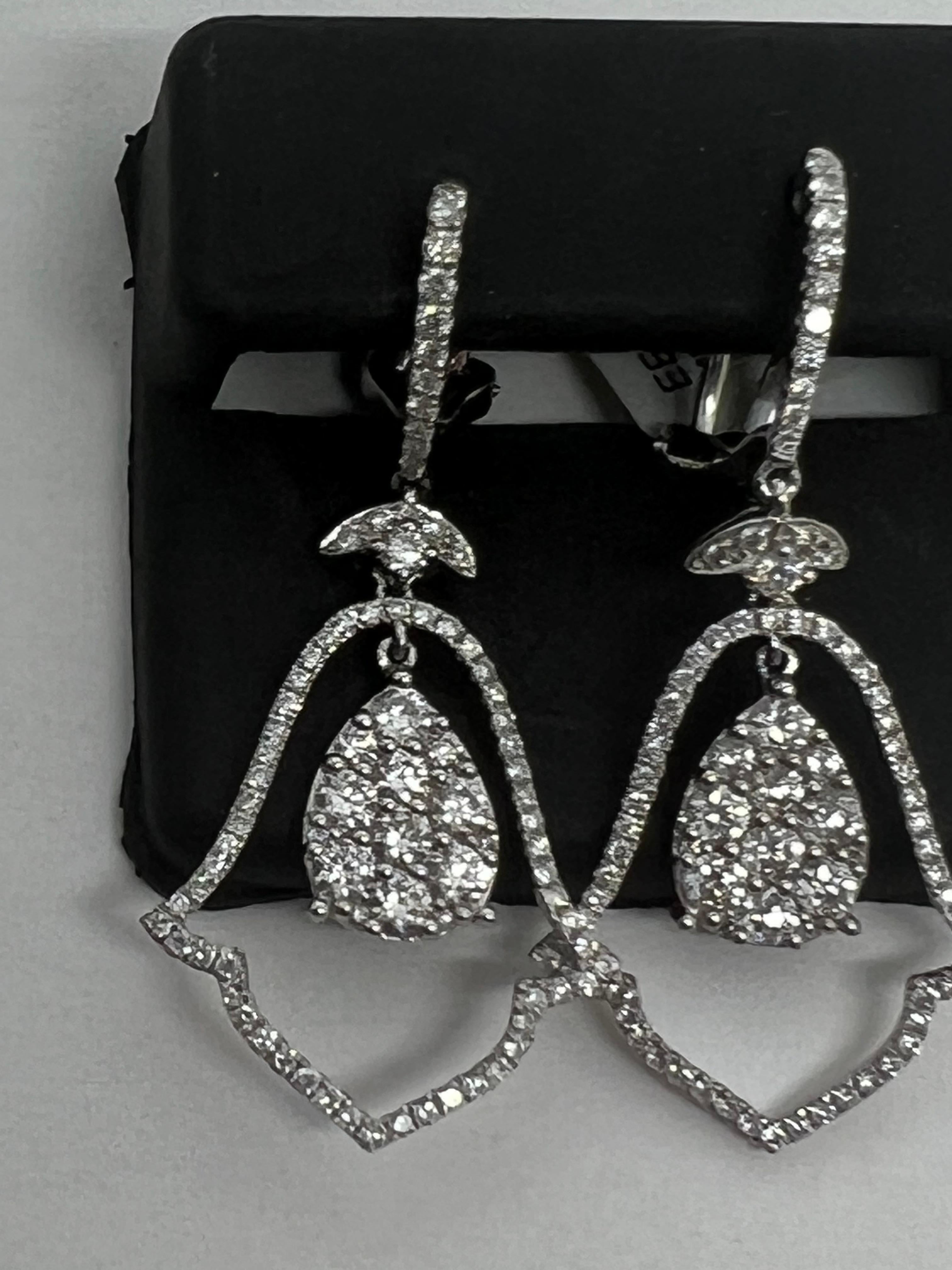 Elevate your jewelry collection with these stunning 14k white gold earrings by K. Bell. Adorned with natural, round-cut diamonds in a pavé setting, these dangle/drop earrings are perfect for any occasion. The white diamond color against the gold