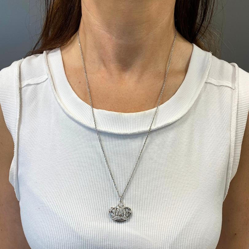 Este collar de oro blanco de 14 quilates, con un colgante en forma de corona con incrustaciones de diamantes. El elegante diseño de la cadena añade un toque contemporáneo, mientras que el intrincado motivo de la corona irradia encanto regio y