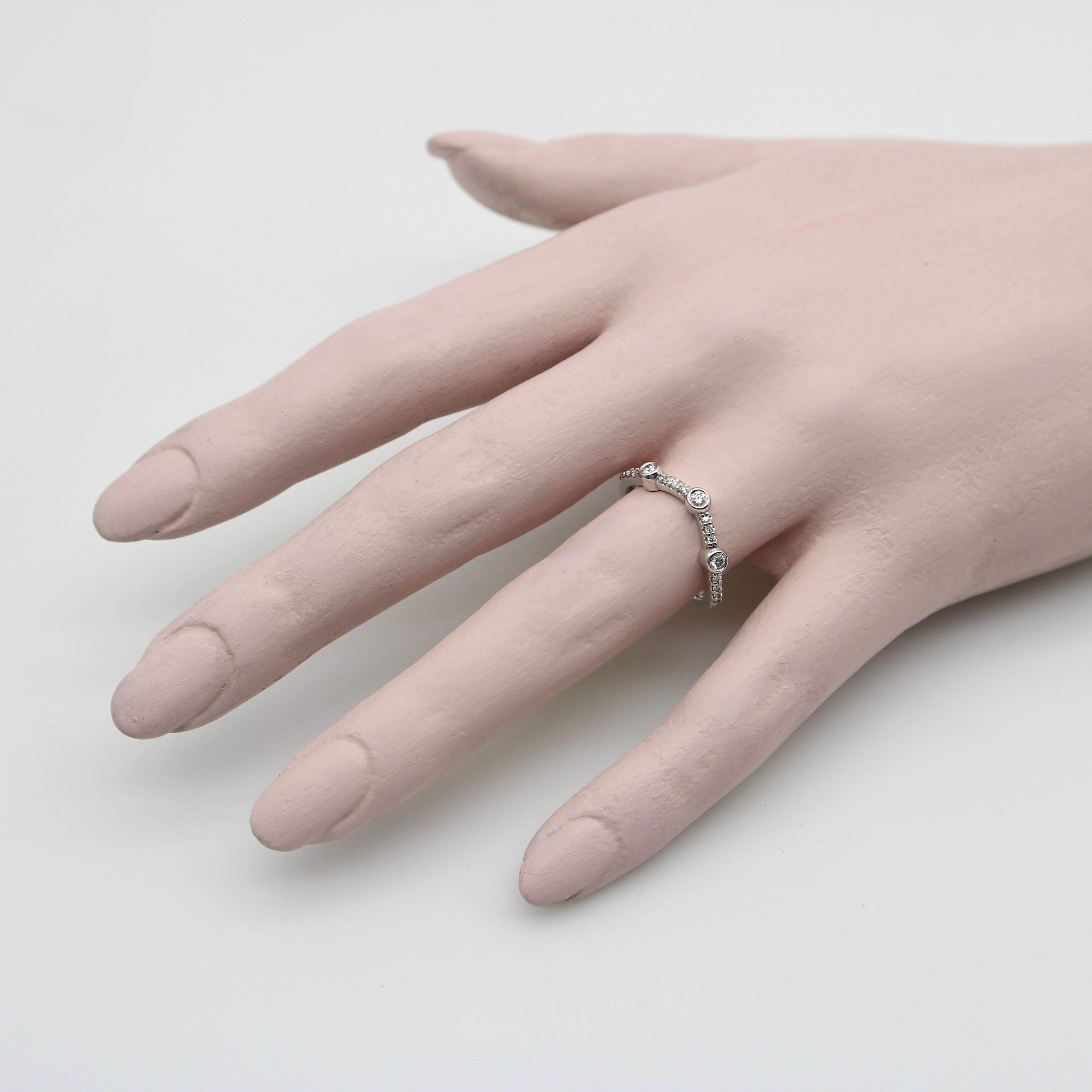 This 14k white gold curved band contains 17 single cut diamonds in an elegant wave shape. Three larger diamonds are bezel set between sections of 14 smaller prong set diamonds, for simple, sophisticated, and fluid line of sparkle. These type of