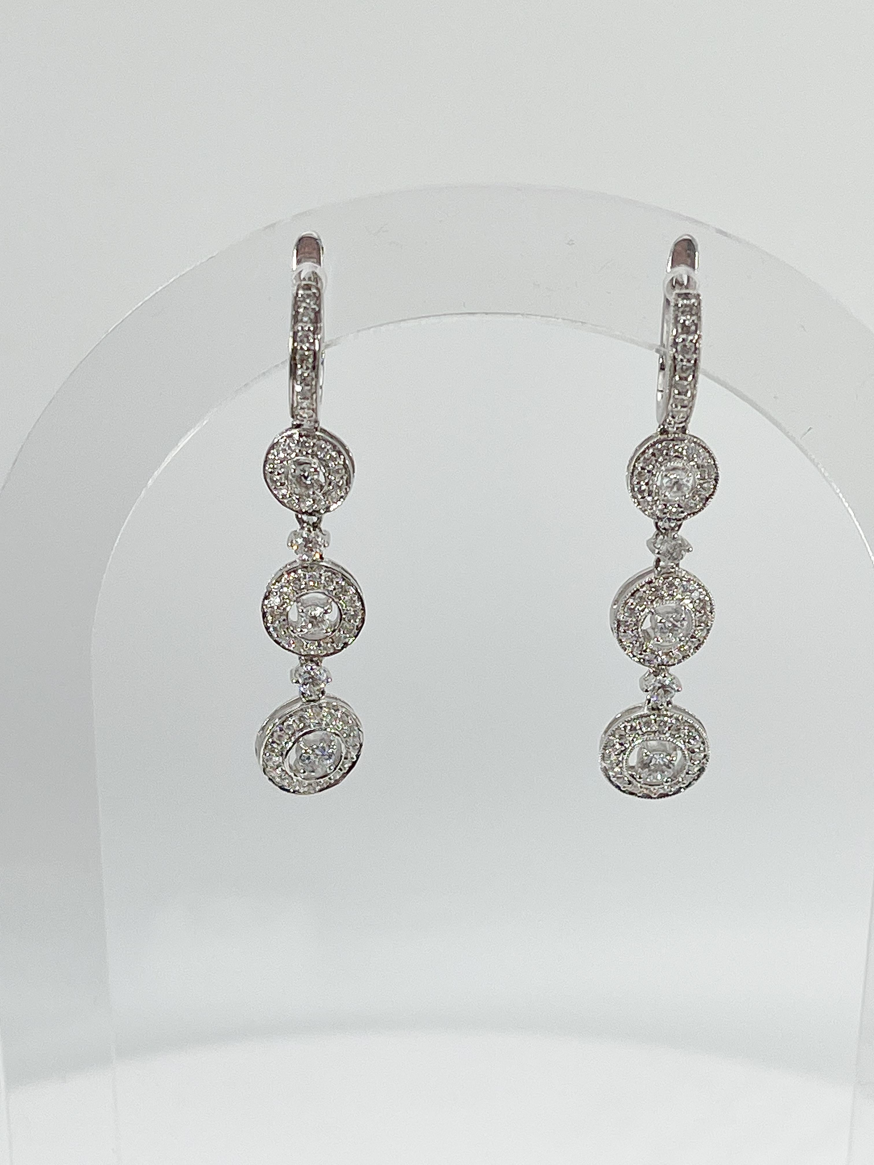 14l white gold diamond dangle earrings. The diamonds in these earrings are all round, they have a width of 8.6 mm, a length of 44 mm, and they have a total weight of 6.4 grams. 