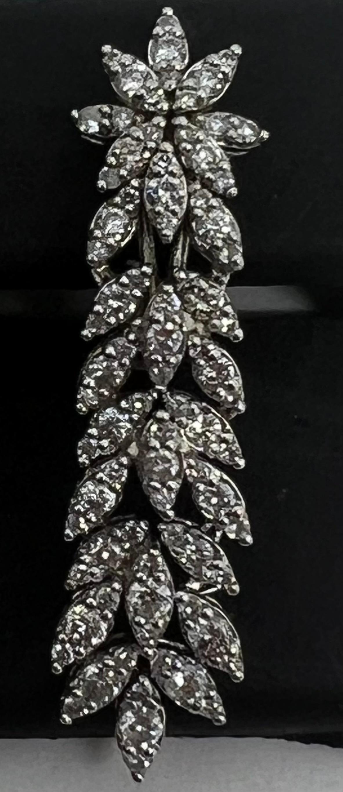 
A stunning pair of dangle earrings made of 14k white gold with a beautiful flower design. The earrings feature a round natural diamond with a total carat weight of 1.05, set in prongs for a secure hold. The white color of the diamond matches the