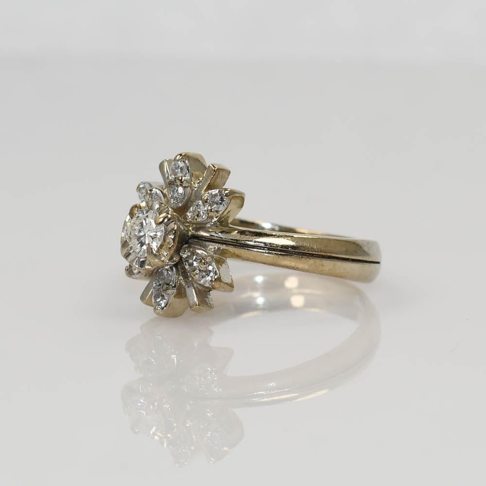 Bague de fiançailles vintage en or blanc 14K.
Le diamant central est de taille ronde brillante et pèse 0,18 carat. Clarté VS2, couleur H.
Il est entouré de 0,12 tdw de diamants de taille unique.
La bague est en forme de fleur,
pèse 4,9 g et est de