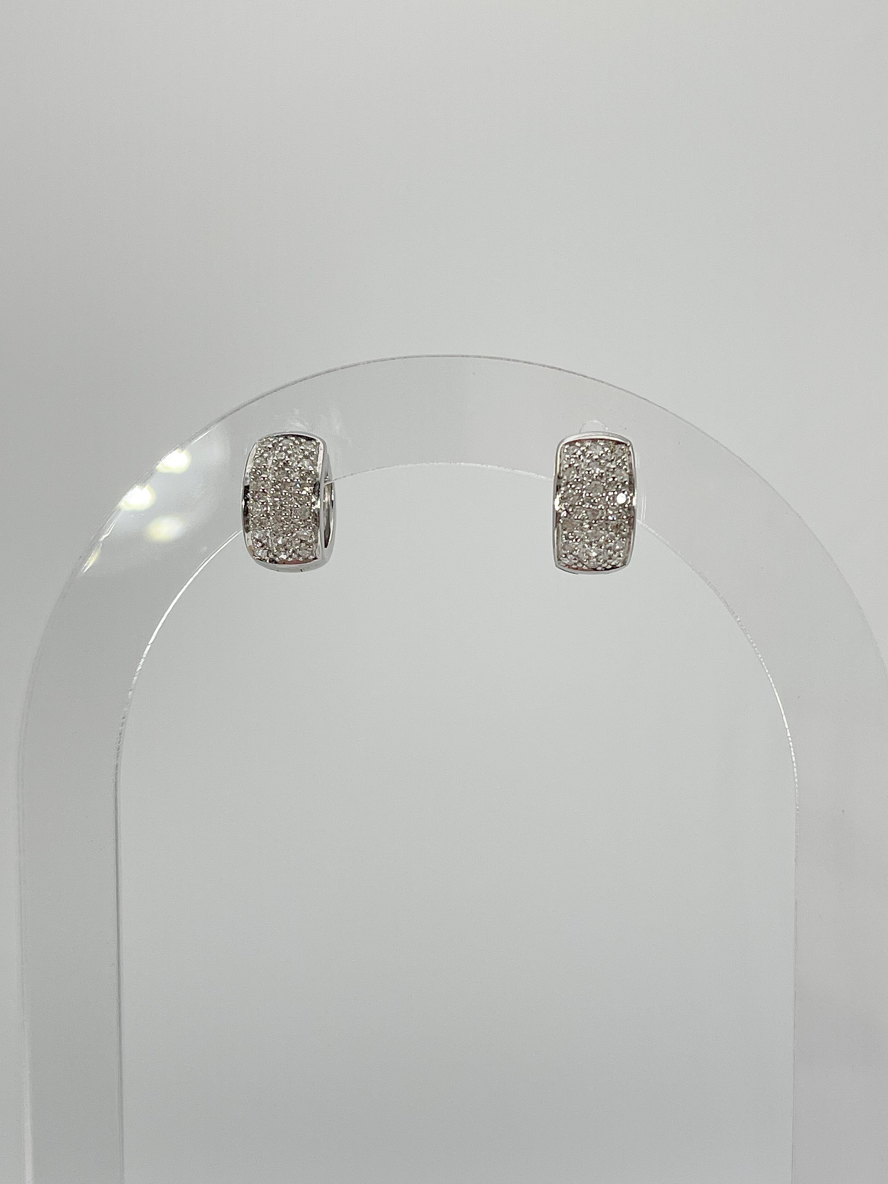 14k white gold diamond huggie hoop earrings. The width of the earrings is 7 mm, the inside diameter is 8.7 mm, and they have a total weight of 4.09 grams. 