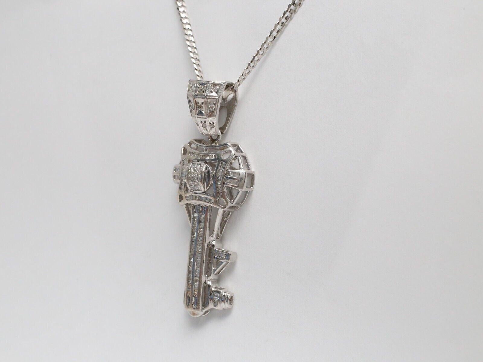 Questo splendido ciondolo a forma di chiave in oro bianco 14K è un pezzo accattivante che unisce l'eleganza a un design audace. Il pendente è impreziosito da diamanti taglio brillante e baguette, disposti in un motivo simmetrico che ne esalta il