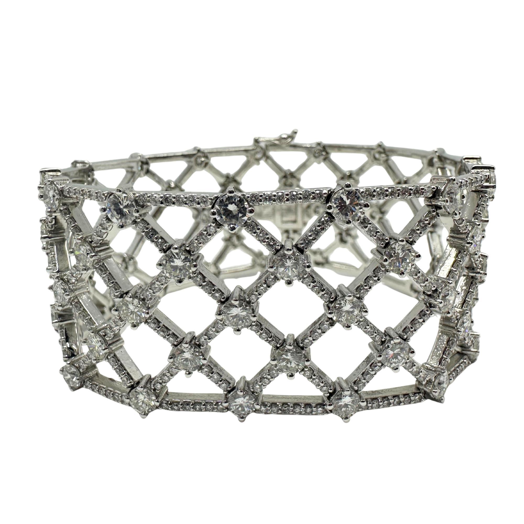 Ein auffälliges Stück mit einem verschlungenen, offenen Gittermuster, das mit 17,56 Karat Diamanten besetzt ist. Die breite, strukturierte Form schafft eine markante, architektonische Silhouette, während sie gleichzeitig das Licht durchlässt und den