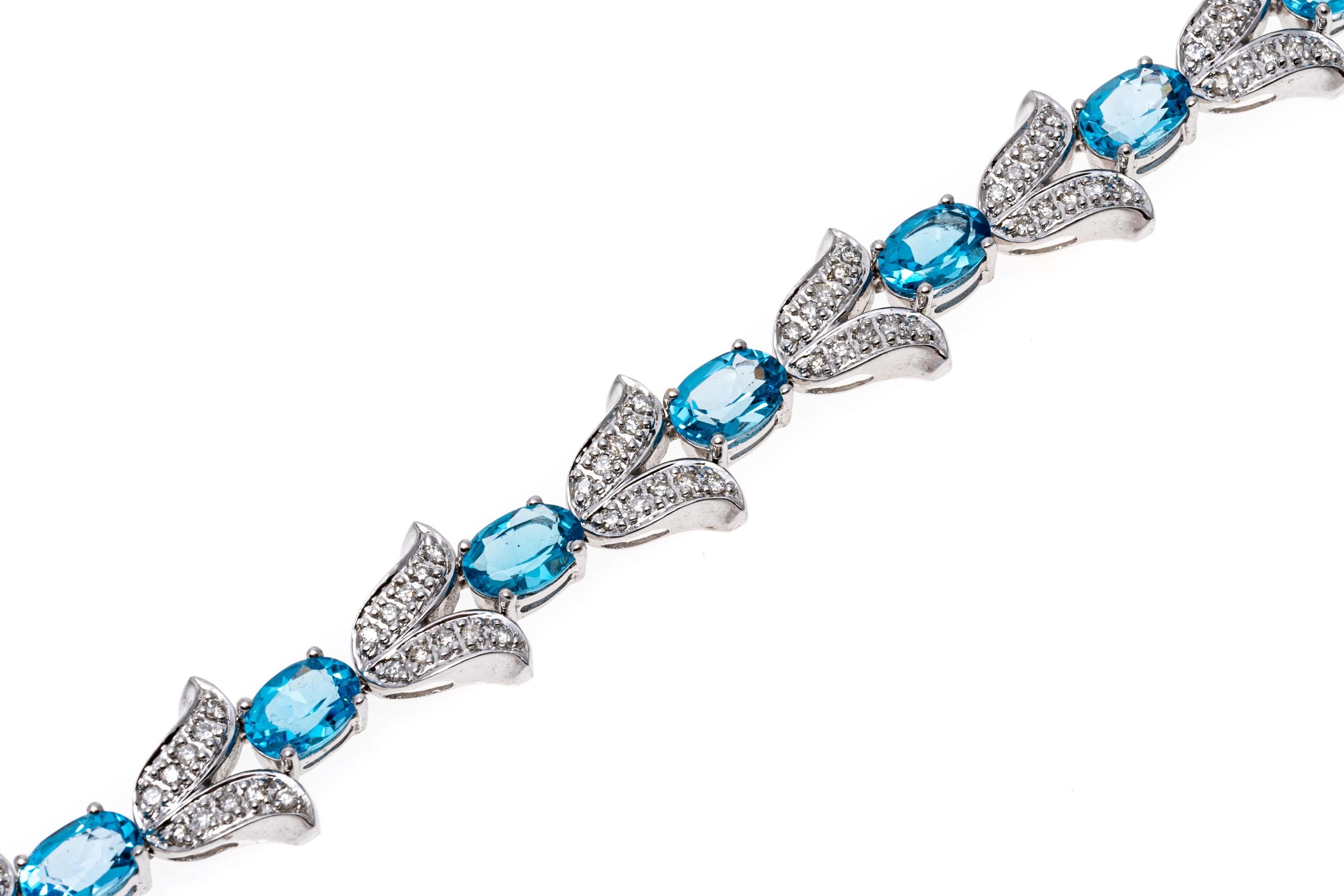 14k white gold bracelet. This gorgeous bracelet features oval faceted, medium blue color blue topaz stones, approximately 10.35 TCW, prong set, alternating with tulip shaped links set with accent diamonds, 0.92 TCW. The bracelet has a hidden box