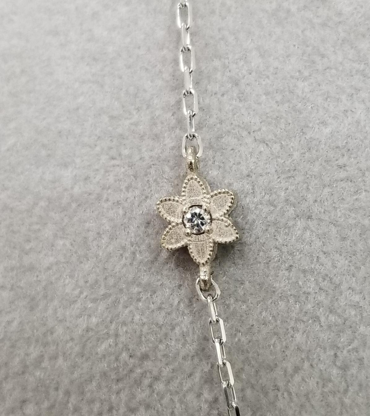 14k white gold diamonds by the yard 2 sided flower necklace, containing 10 round full cut diamonds of very fine quality weighing .20pts. on a 18 inch chain.