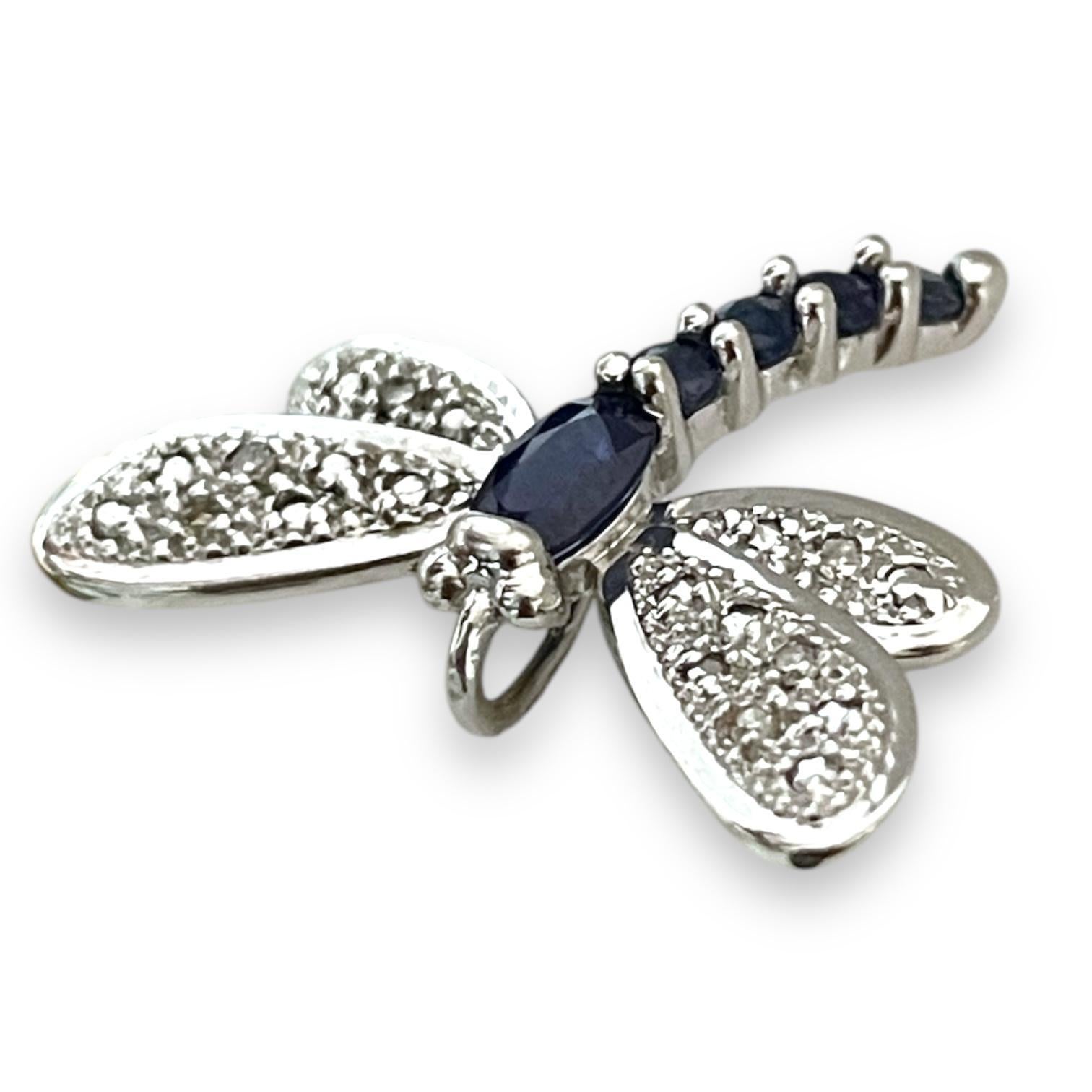 Un delicato ed elegante ciondolo a forma di libellula realizzato in oro bianco 14K, con ali tempestate di diamanti e corpo ornato da vibranti zaffiri blu. Questo splendido pezzo simboleggia la trasformazione e la bellezza, perfetto per aggiungere un