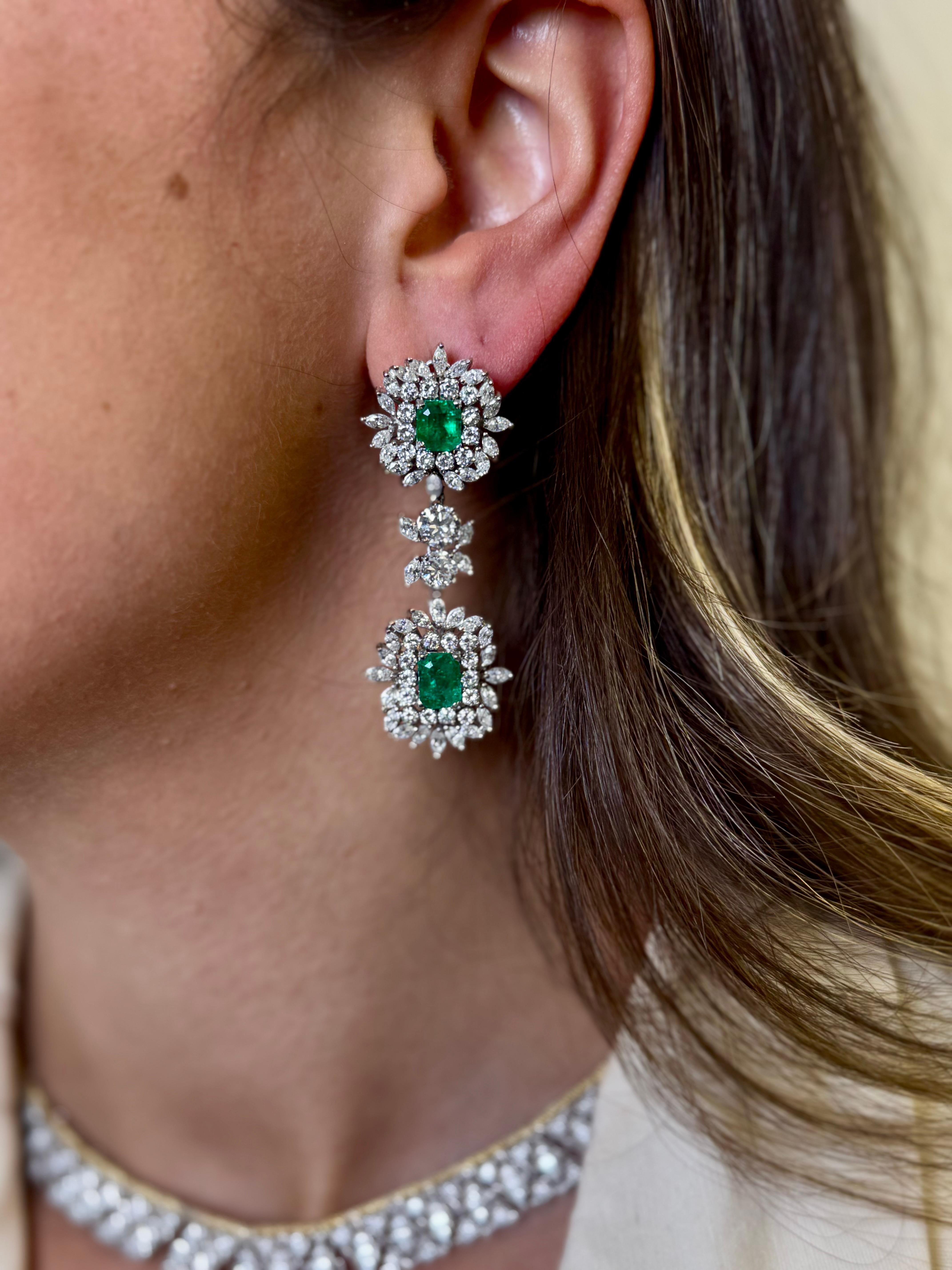 A striking pair of vintage double drop earrings crafted in 14K white gold (stamped 585), showcasing four vibrant green emeralds with a total weight of approximately 6.72 carats. Each emerald is framed in a dazzling surround of mixed-cut