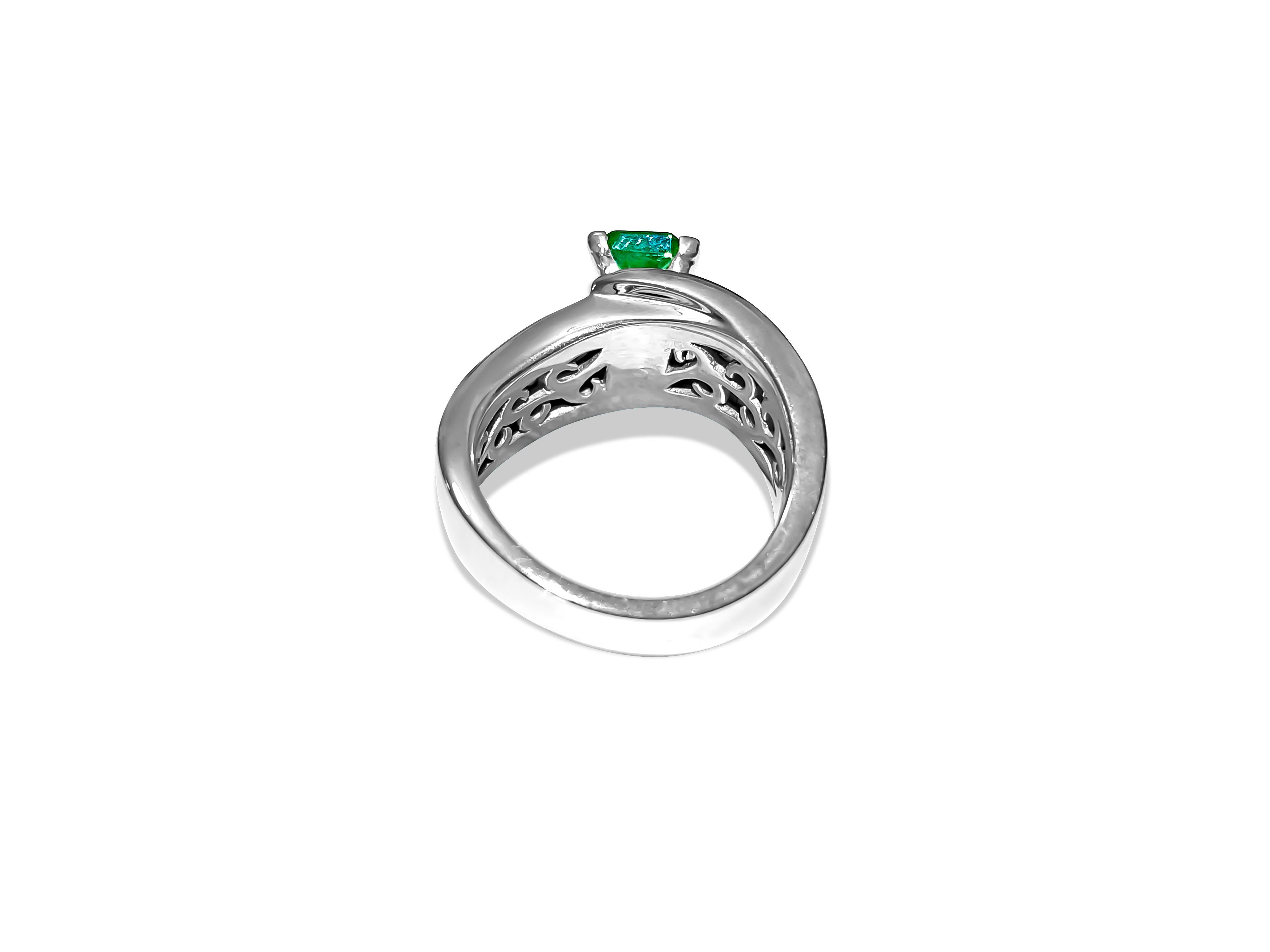 Crafted from solid 14k white gold, this exquisite engagement ring features a stunning 2.00-carat emerald center stone, showcasing excellent color and saturation in an emerald cut and set securely in prongs. Adorning the sides are 1.31 carats of