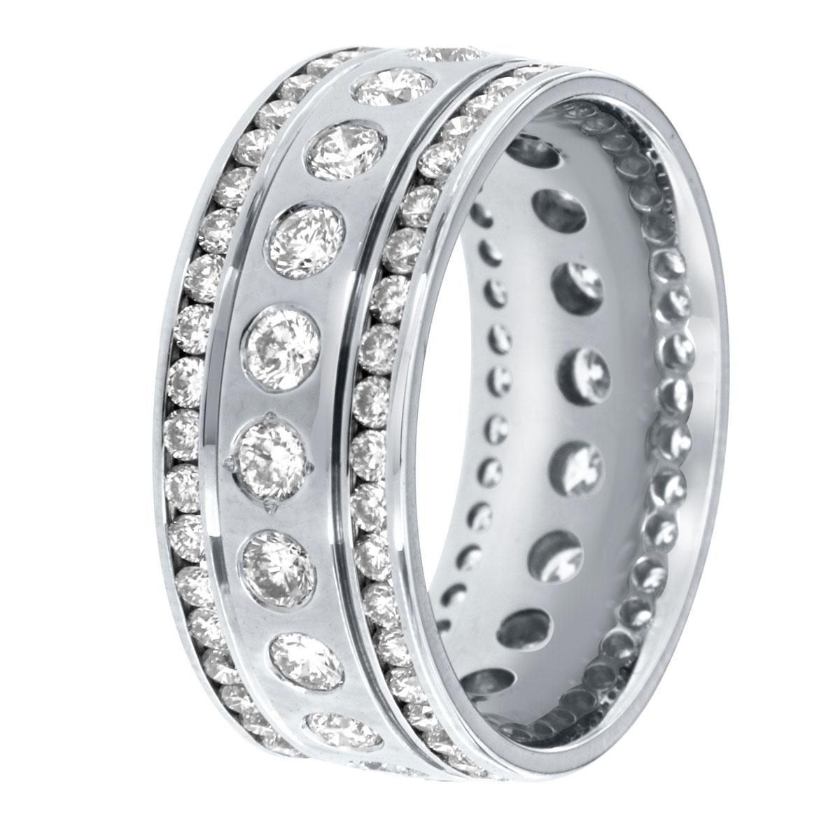 This 14k white gold eternity band features a center row of brilliant round diamonds scattered and a bezel set. It is flanked by two rows of diamonds channel set that creates this royalty design. The band is 8.5 mm wide. The current finger size is 7.