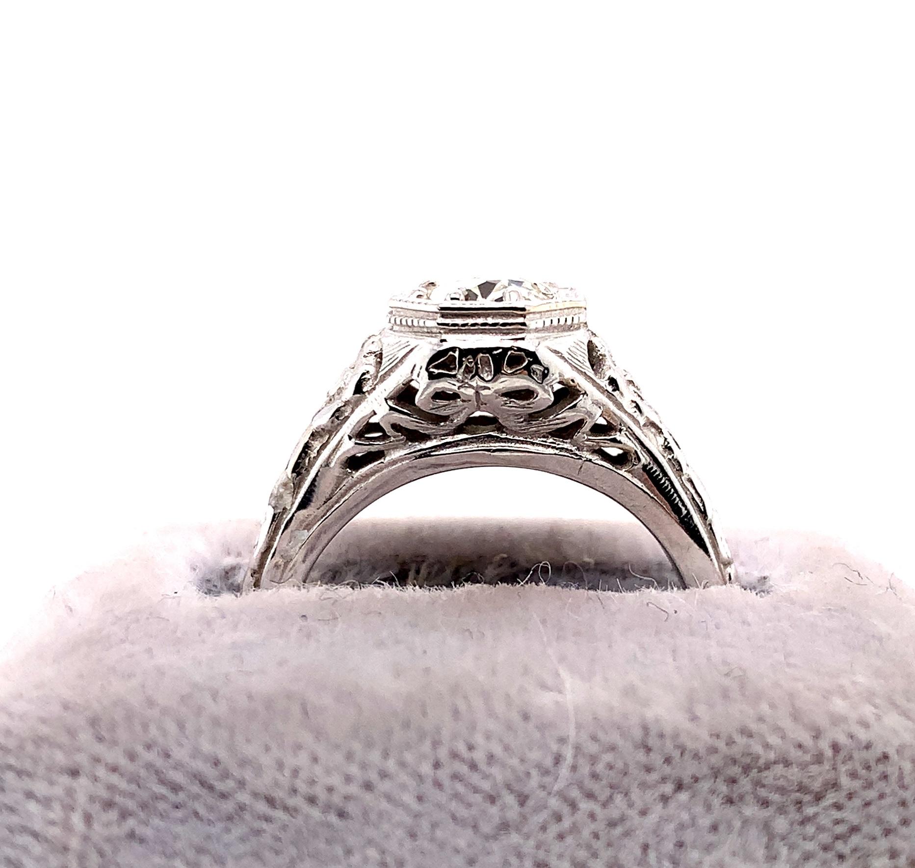 14K white gold filigree ring featuring an European cut diamond weighing about 3/4 carat. The diamond has SI2 clarity and I-J color. It measures about 6mm. The antique diamond is set in a beautiful modern filigree setting with ribbons and flowers.