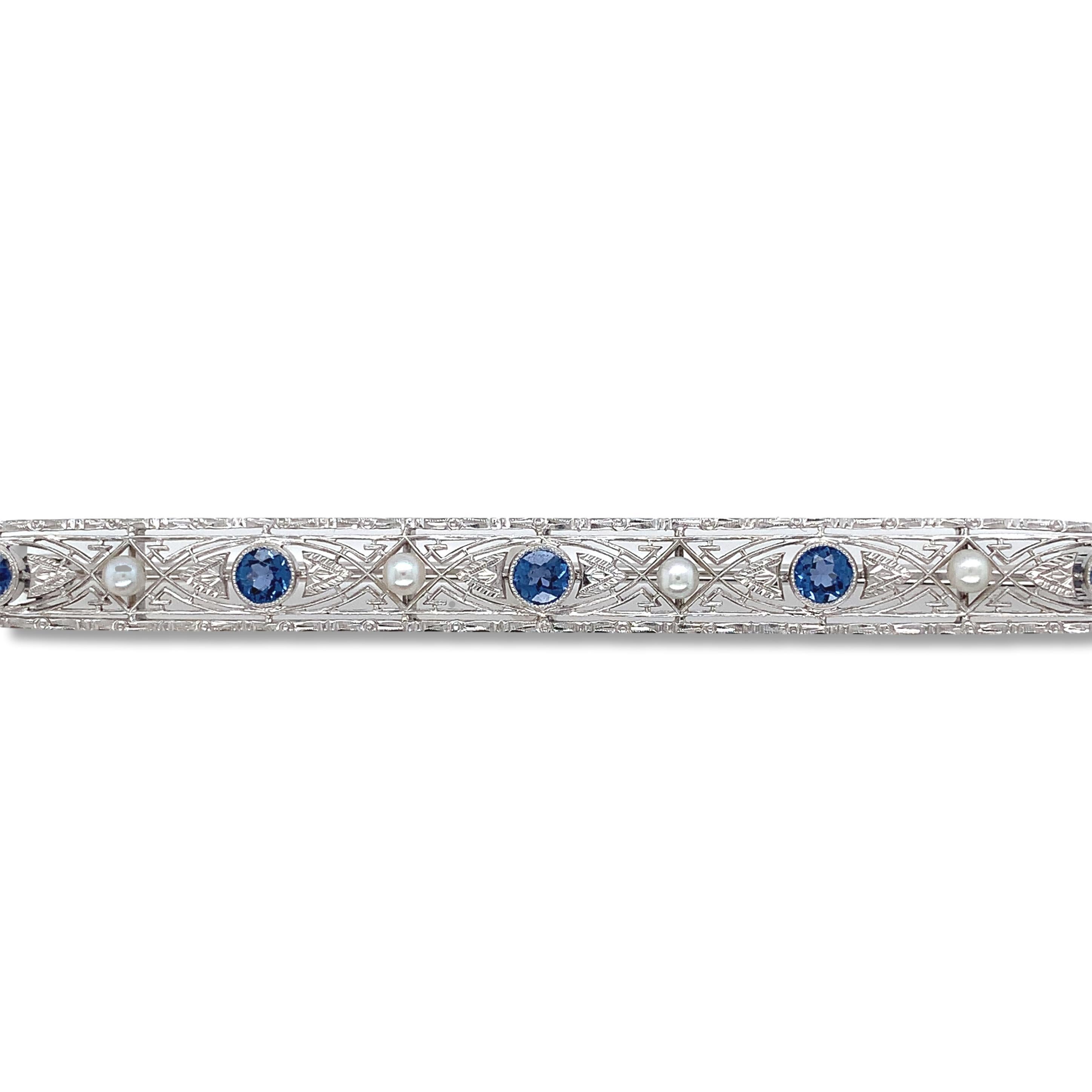 14K White gold filigree bar pin brooch featuring 5 cornflower blue Montana sapphires and seed pearls. GIA report#2235187921 states round brilliant cut natural unheated blue sapphires from Yogo Gulch. The sapphires measure 3.32mm x 3.35mm x 1.75mm.