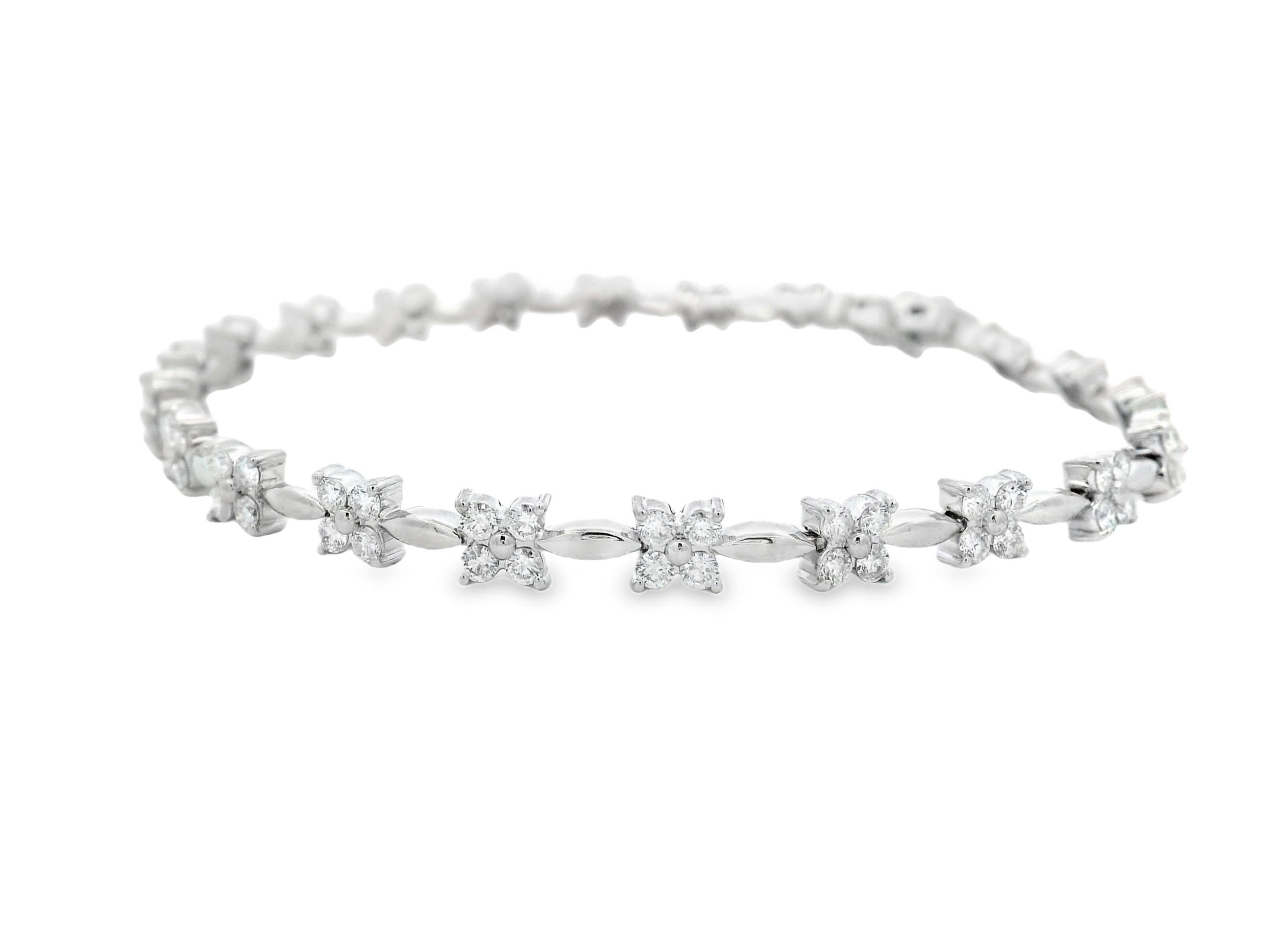 Esta refinada pulsera floral de diamantes en oro blanco de 14 quilates presenta 88 diamantes brillantes redondos que suman un total de 2,00 quilates. Cada diamante está engastado en pavé dentro de un delicado motivo floral de cuatro pétalos, unidos