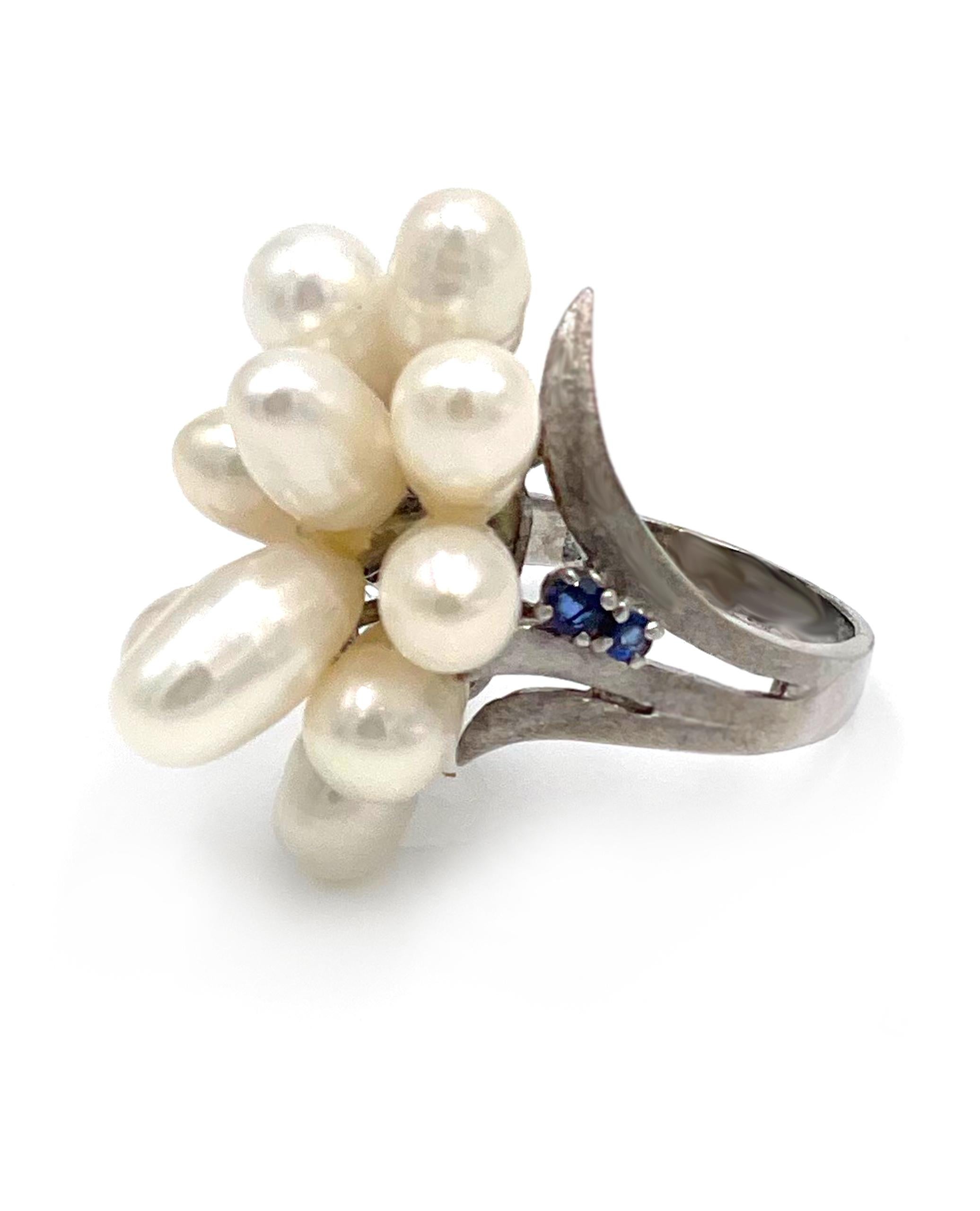 Preowned 14K white gold fresh water pearl and sapphire cocktail ring. The setting is peg set with half drilled oblong
fresh water pearls ranging from 10.0x5.6mm to 6.0x5.0mm. The ring is accented with four round faceted
deep blue sapphires averaging