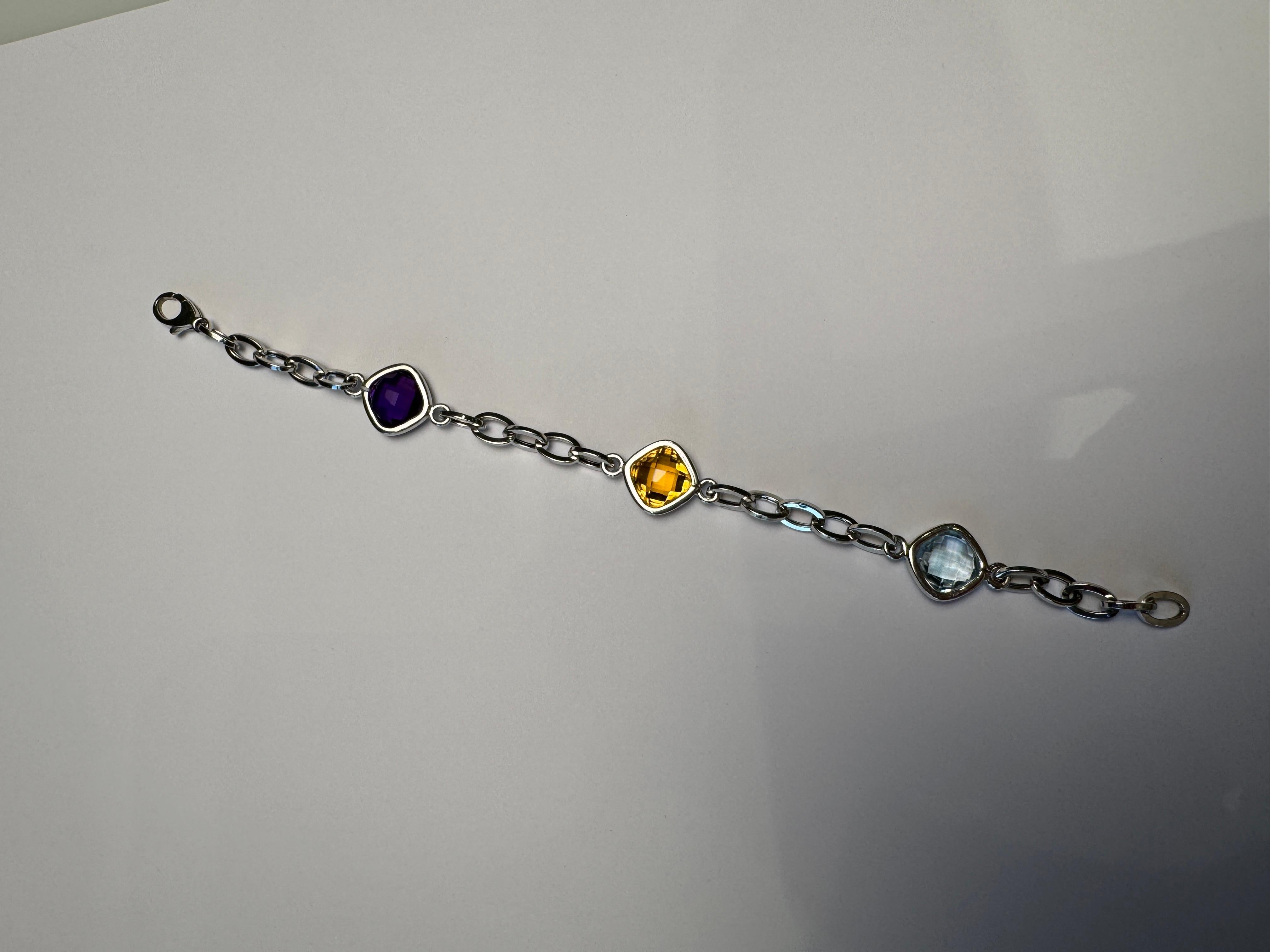 Ce bracelet moderne de 7,5 pouces en or blanc massif 14k de 9 grammes met en valeur un trio de pierres précieuses taillées en coussin et serties d'un chaton : une topaze bleue brillante, une citrine jaune ensoleillée et une améthyste violette