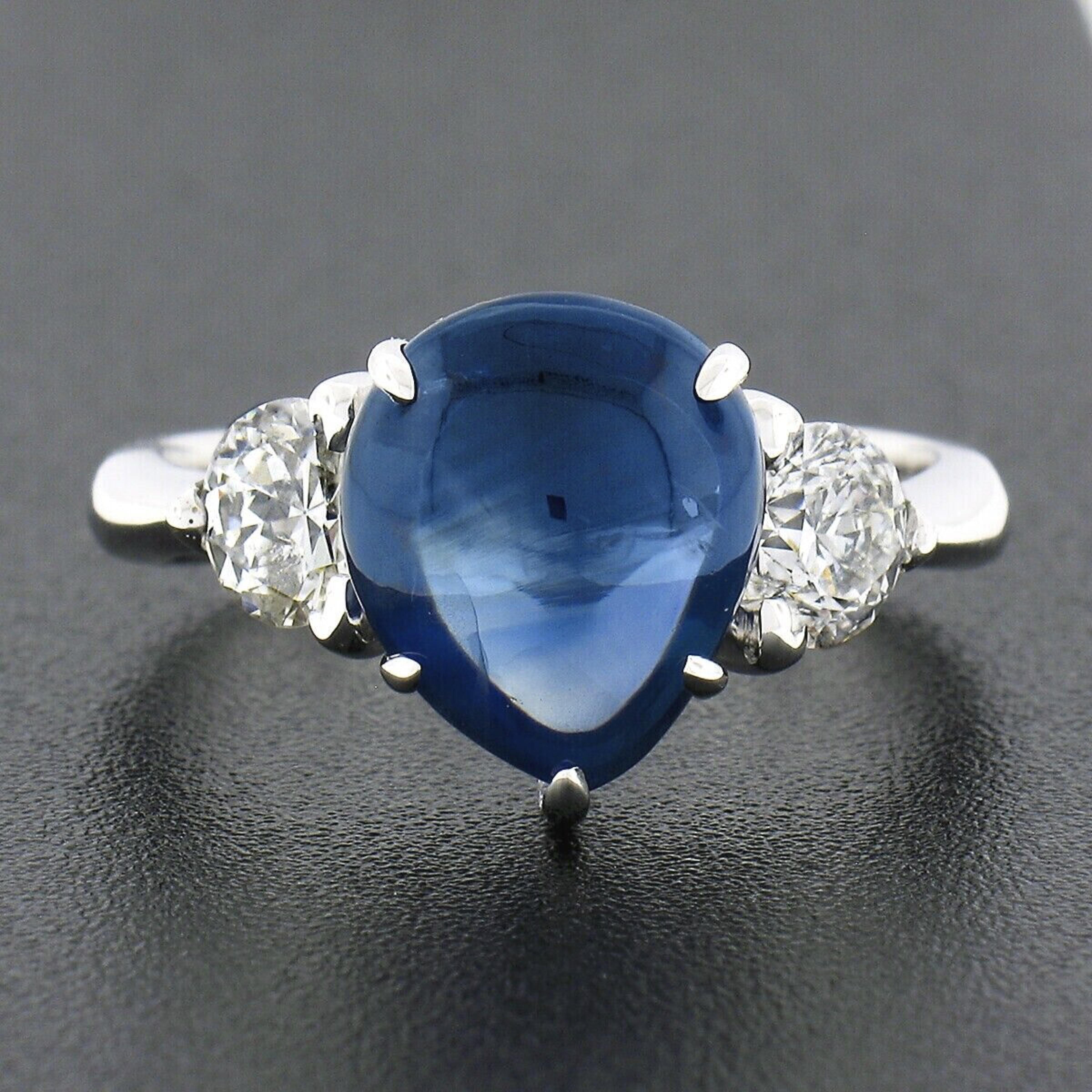 You are looking at a truly unusual and fabulous looking sapphire and diamond three stone engagement ring that is crafted in solid 14k white gold. The ring features a gorgeous, GIA certified, pear cabochon cut sapphire solitaire neatly prong set in
