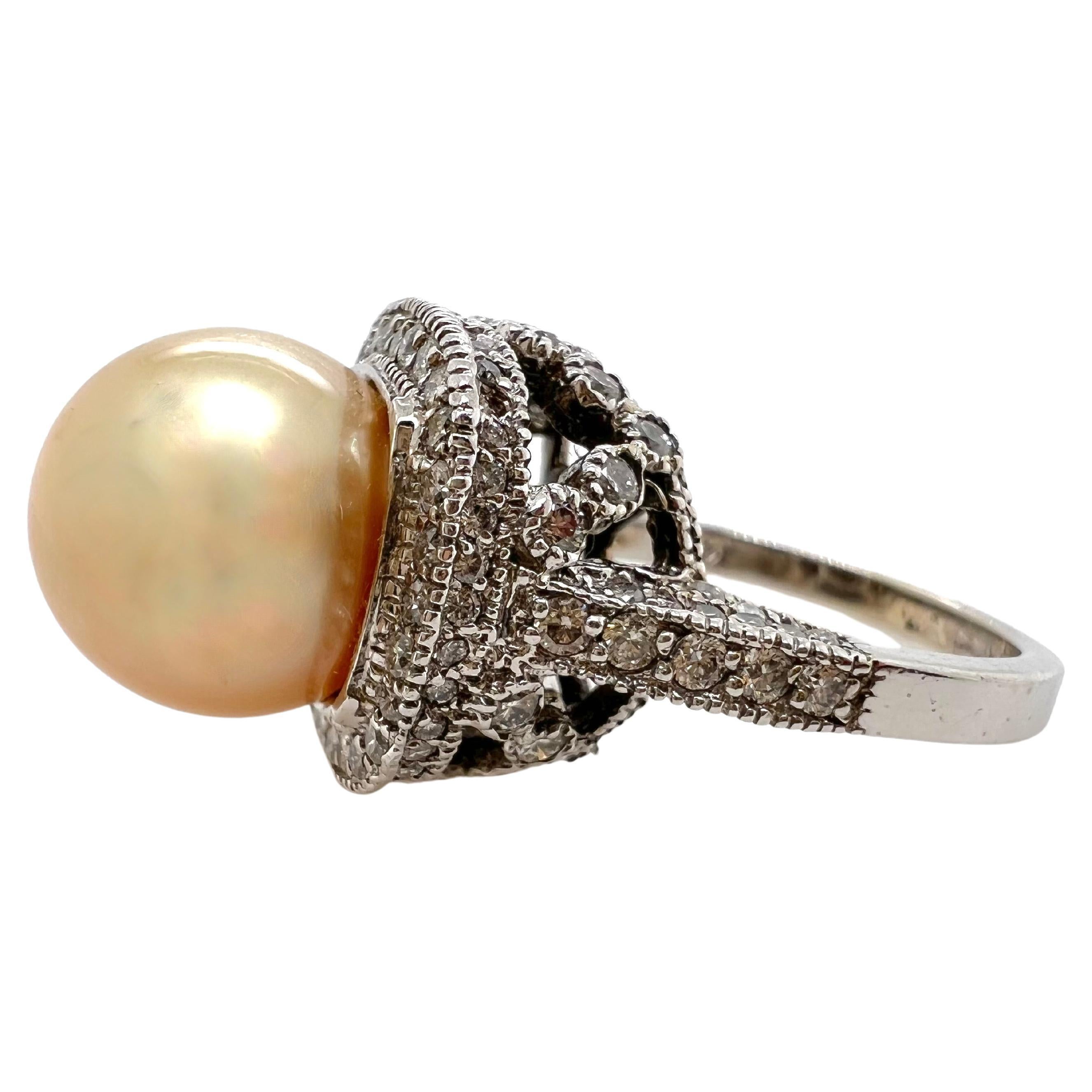 Cette magnifique perle dorée des mers du Sud est posée sur un lit de diamants dans cette monture artistique qui accentue le lustre et la couleur de la perle.  La perle mesure 11,50 mm et repose sur une belle monture avec des diamants sur le profil