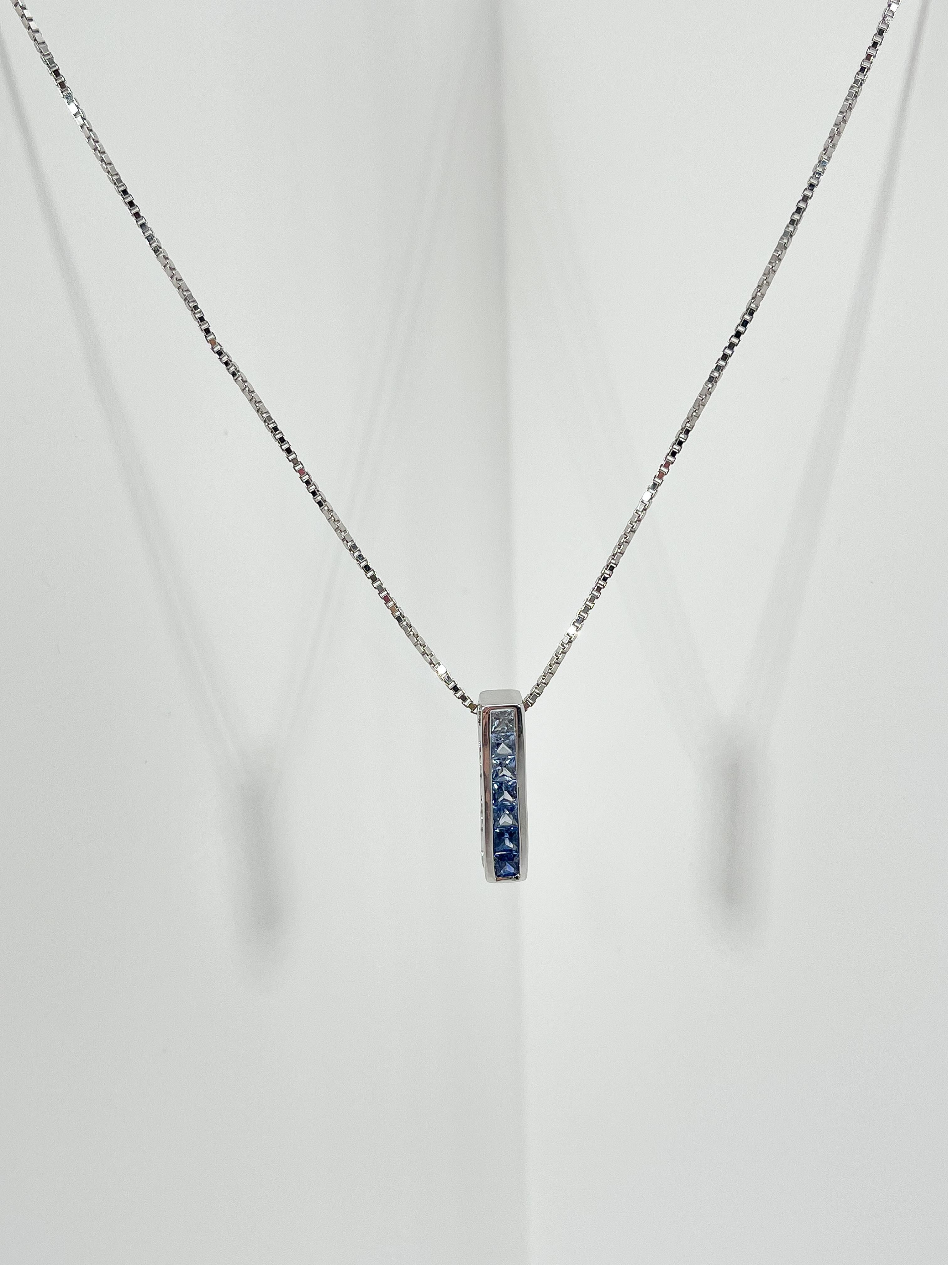 14k white gold gradient blue sapphire pendant necklace. 7 sapphires, all different colors going from lightest to darkest, all stones are princess cut. The pendant comes on a box chain and the chain is 18 inches in length. The pendant measures 18.7 x