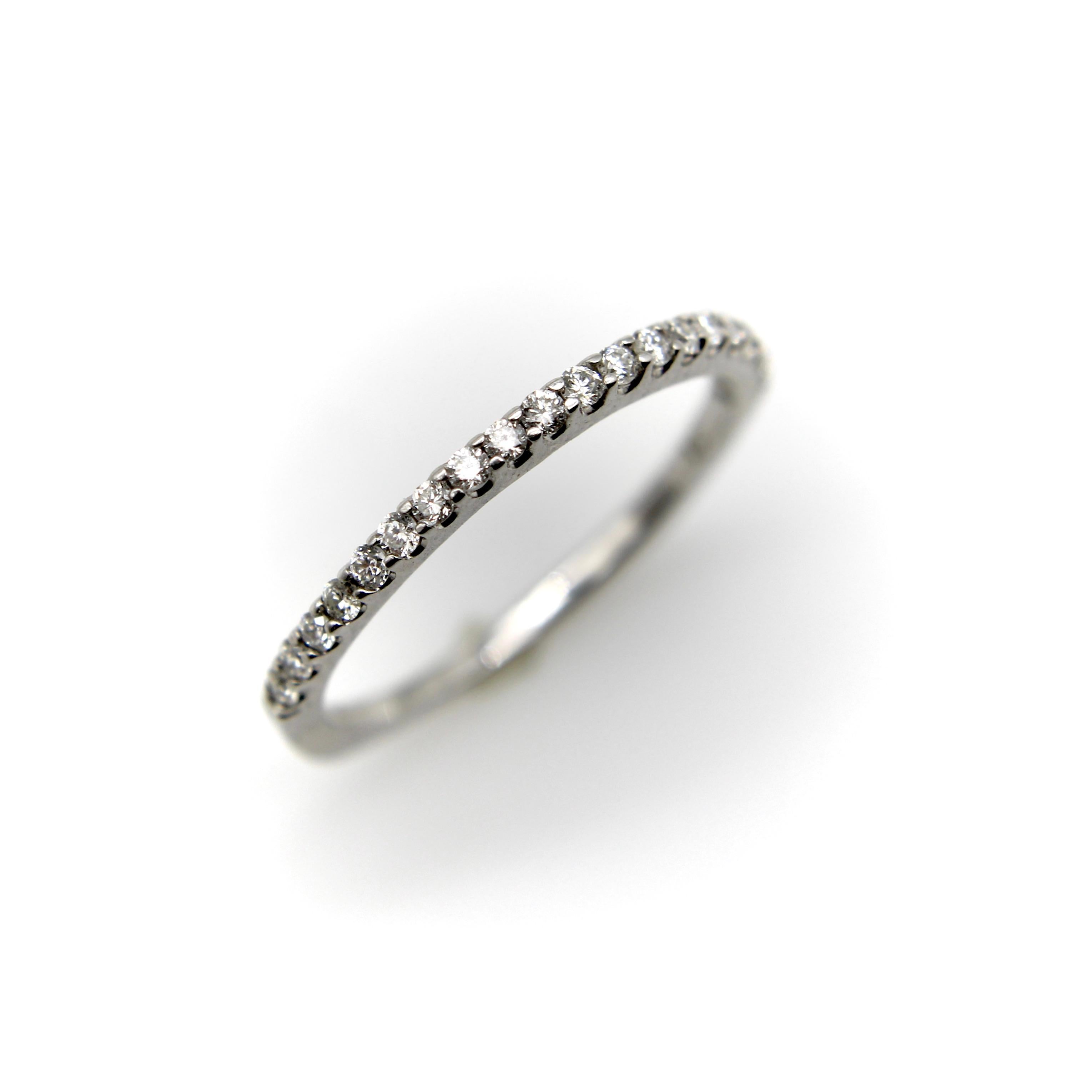 Dieser Ewigkeitsring aus 14 Karat Weißgold verfügt über 27 perlenbesetzte Diamanten, die eine funkelnde Linie entlang der oberen Hälfte des Rings bilden. Die untere Hälfte des Rings hat eine quadratische Form, so dass der Ring gut an der Hand