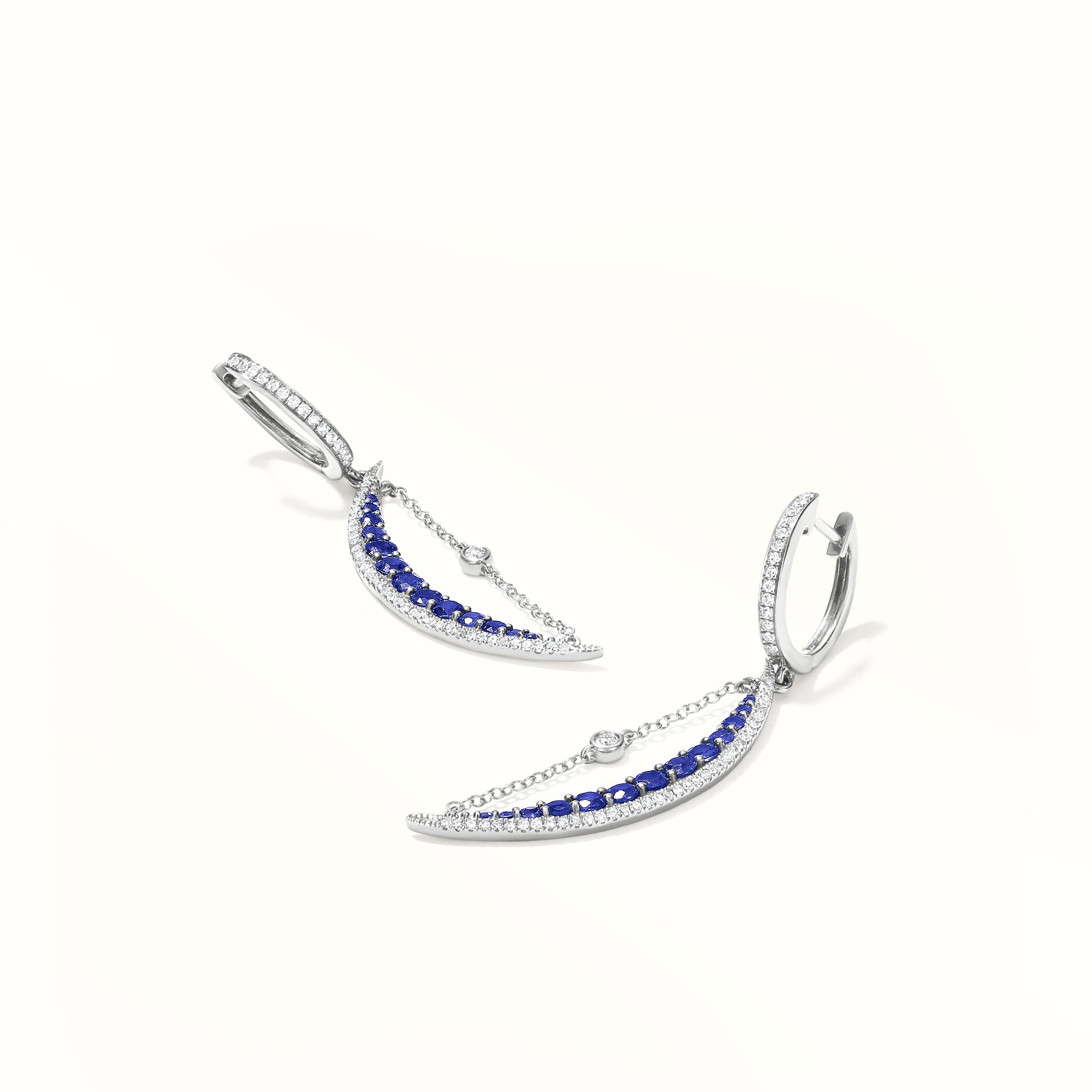 A stunning pair of Gemistry half-moon-shaped earrings with 26 round faceted brilliant blue sapphires set in pave. The piece is made of 14 Karat white gold and is encrusted with 104 round single-cut diamonds. Earrings with hugger clasps that lock