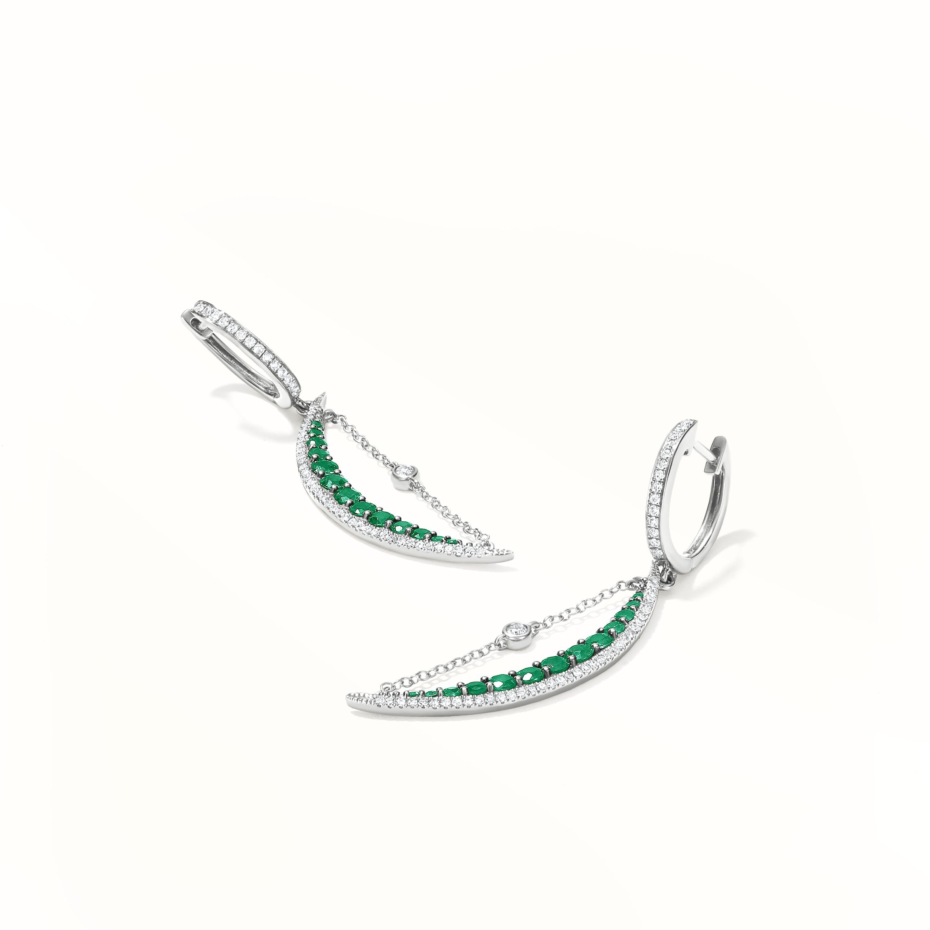 A stunning pair of Gemistry half-moon-shaped earrings with 26 round faceted brilliant Emerald set in pave. The piece is made of 14 karat white gold and is encrusted with 104 round single-cut diamonds. Earrings with hugger clasps that lock into place