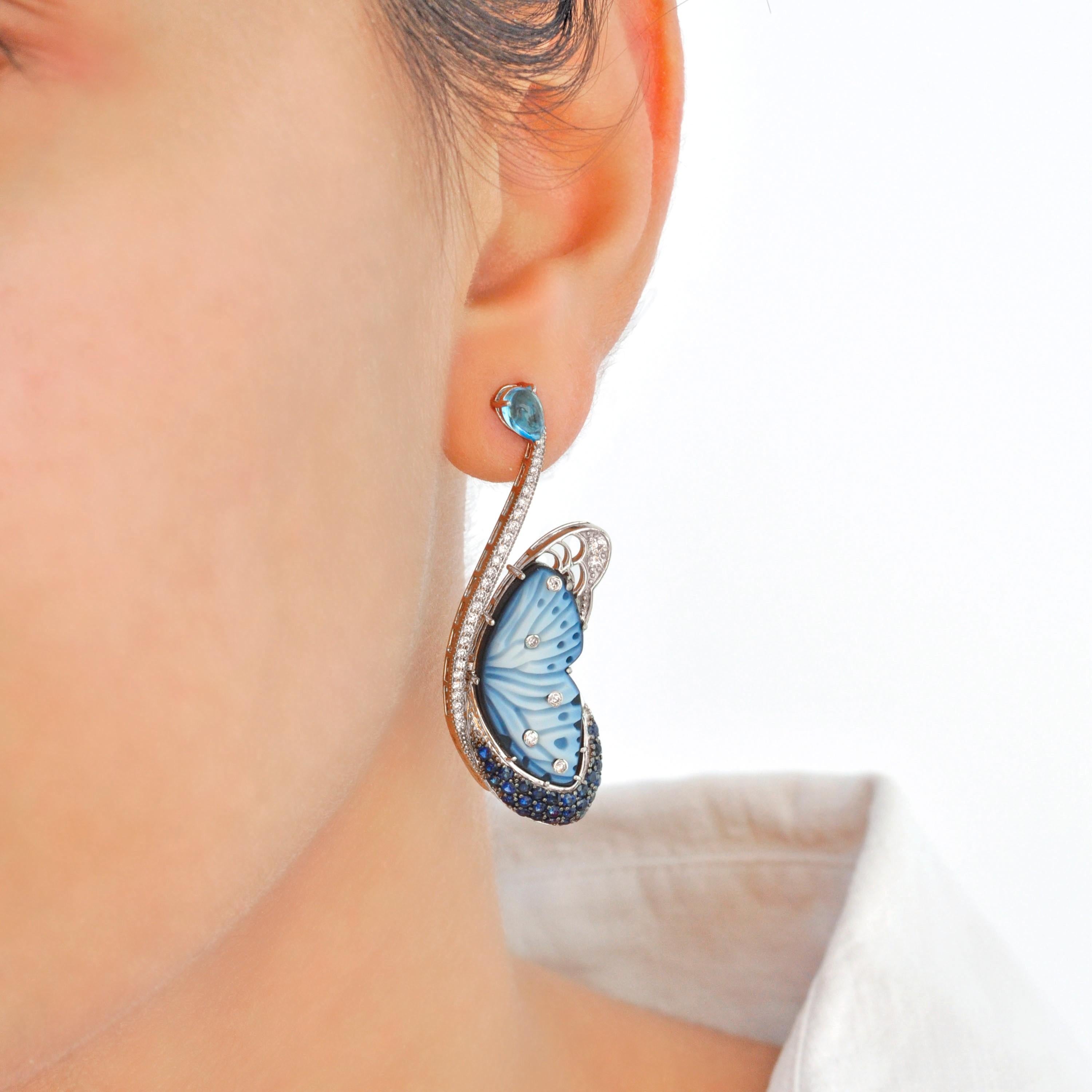 These 14K White Gold Hand-Engraved Agate Butterfly Topaz, Blue Sapphire, and Diamond flutter Earrings are a breathtaking tribute to nature’s elegance, meticulously crafted with an exceptional blend of artistry and innovation. The highlight of these
