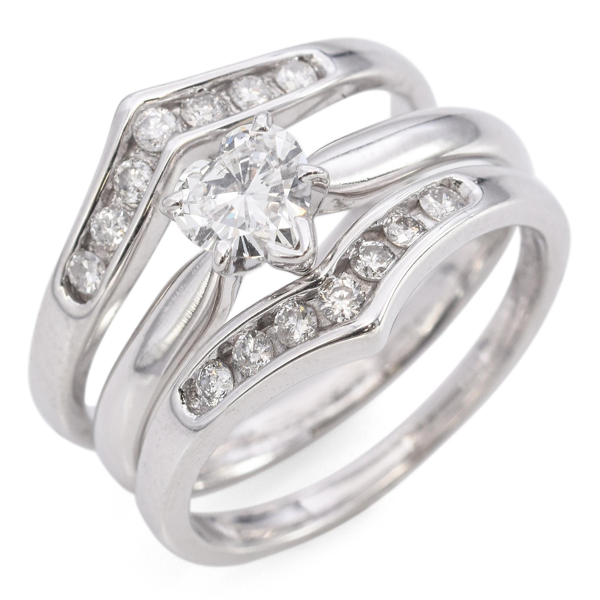 Elegant 14k White Gold Heart Diamond Engagement and Wedding Ring Set. Featuring a heart-cut solitaire diamond ring as the center ring, weighing approximately 0.43 carats, the primary ring is complemented by diamonds in sleek, modern bands of channel