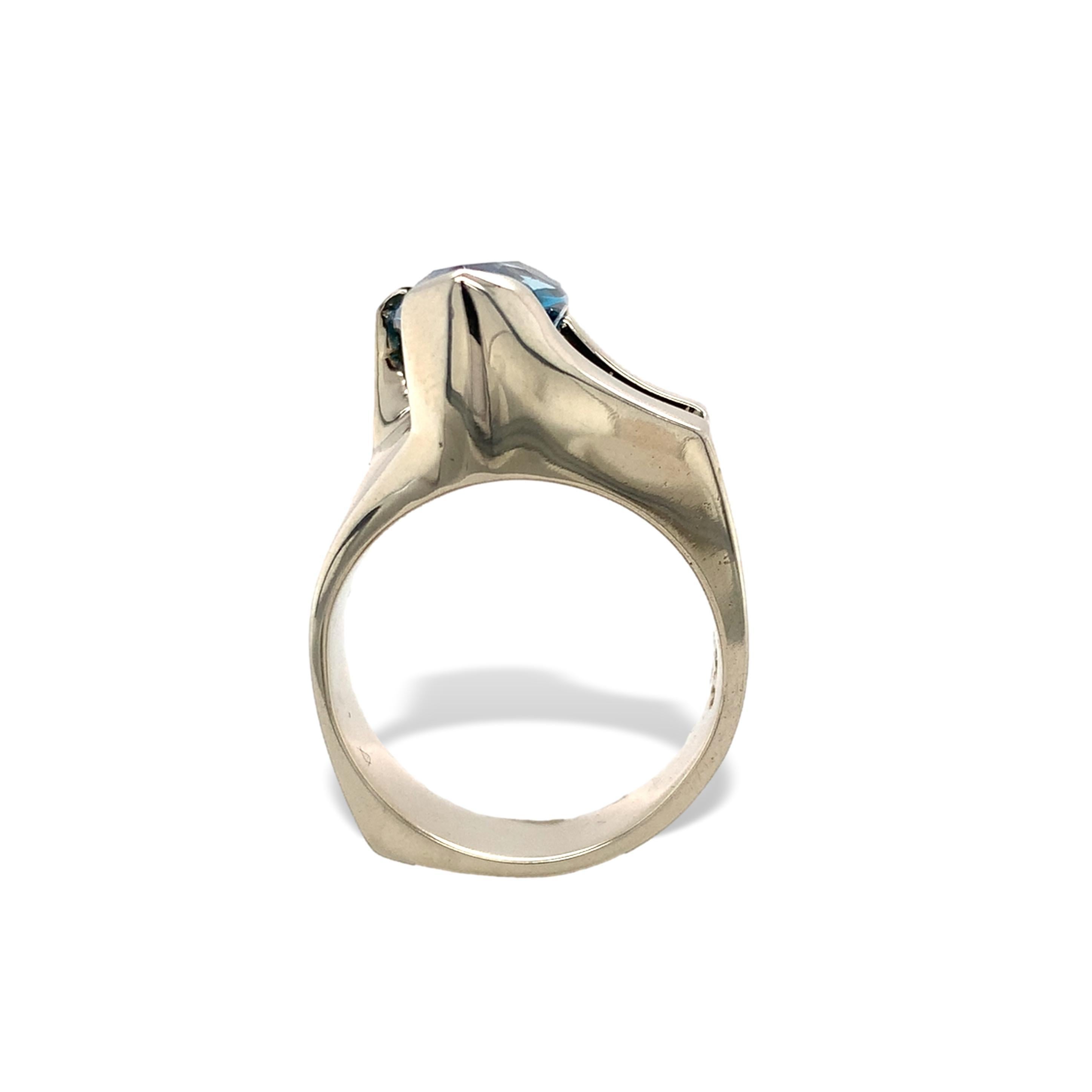 Anello moderno e personalizzato in oro bianco 14K con topazio blu.  C'è un topazio blu dal taglio particolare e triangolare, di colore verde acqua scuro. Il topazio misura circa 13,5 mm x 8 mm. L'anello misura 1/2