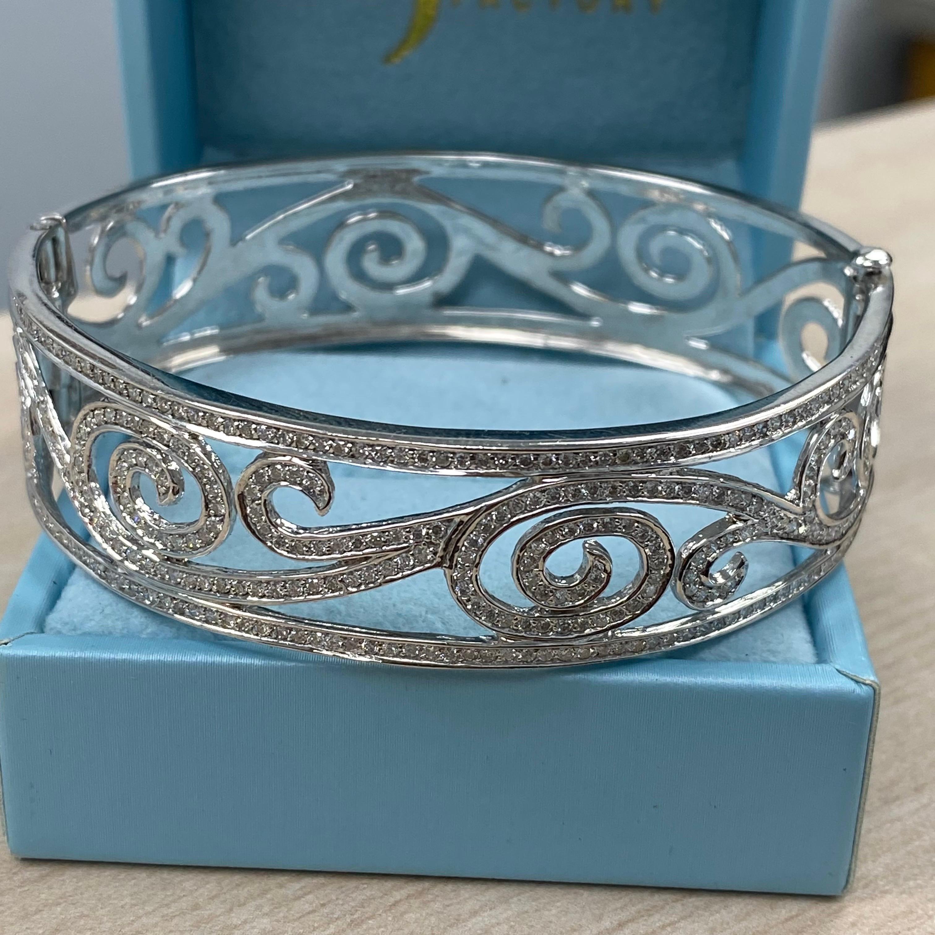 Ce magnifique bracelet à diamants est fabriqué avec expertise à partir d'un luxueux mélange d'or blanc 14k de 26,8 grammes. Il présente de délicats accents en forme de vagues, élégamment nichés entre deux rangées de diamants étincelants. Avec un