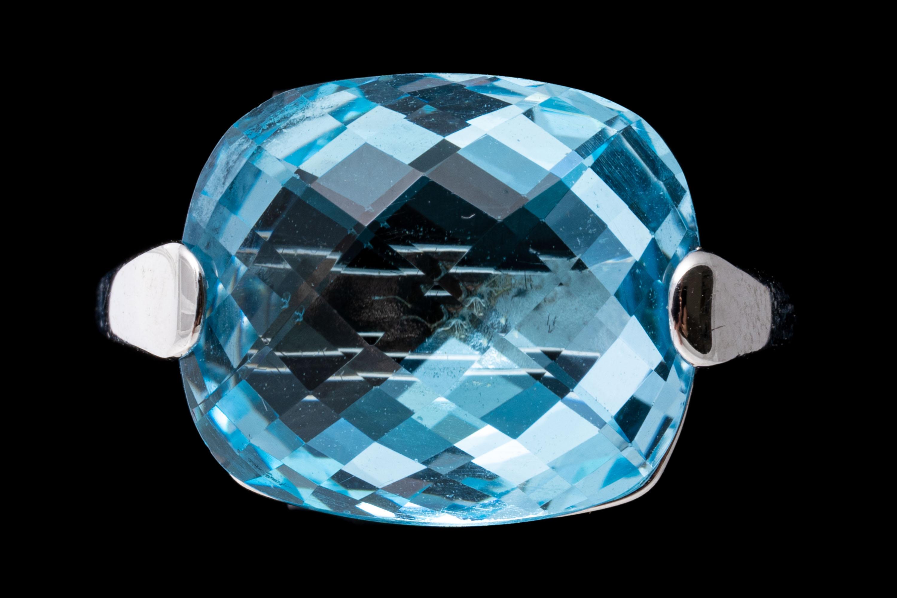 14k white gold ring. This lovely contemporary ring is a horizontal, rectangular checkerboard cushion, light blue color blue topaz, approximately 8.51 CTS, set atop a narrow, airline style shank with two wide prongs.
Marks: 14k
Dimensions: 1/2