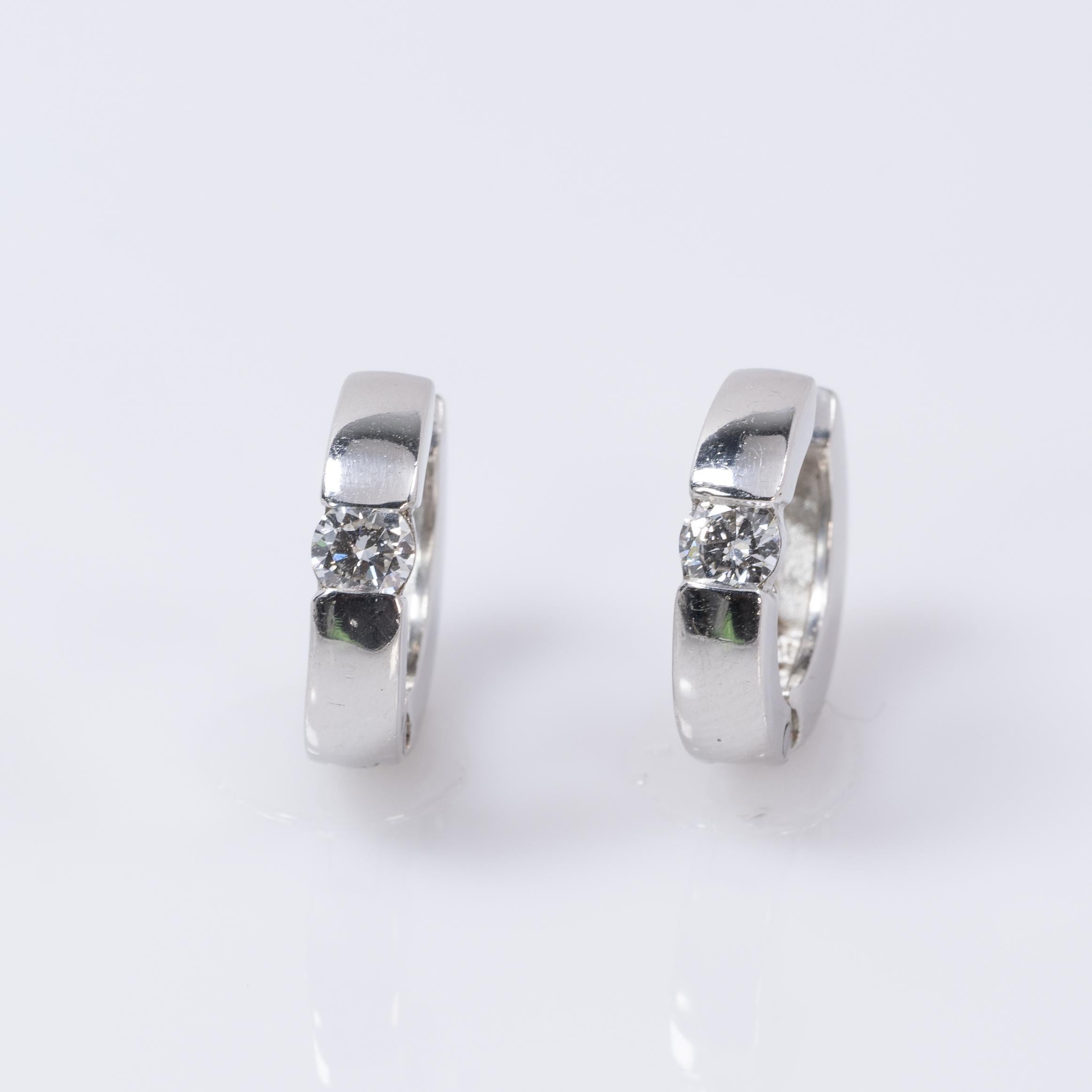 Diese exquisiten Ohrringe im Huggie-Stil sind aus 14 Karat Weißgold gefertigt und strahlen zeitlose Eleganz aus. Jeder Ohrring ist mit einem schimmernden Diamanten verziert, der so gefasst ist, dass er das Licht aus jedem Winkel einfängt. Der