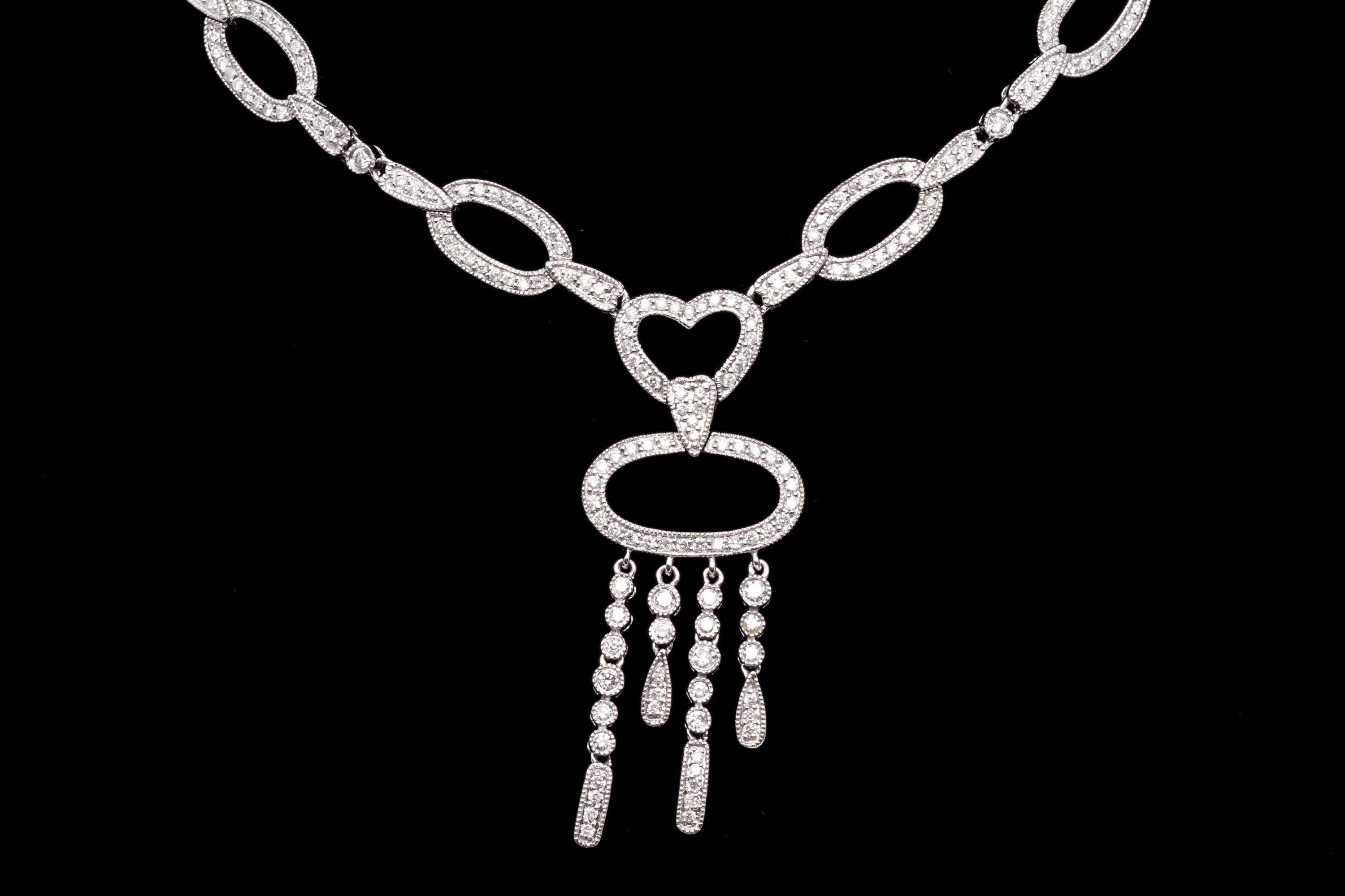 14k white gold necklace. This impressive necklace is a high polished white gold, articulated link that centers to open, round faceted diamond set horizontal oval links that lead to a heart center, diamond set, and a horizontal oval drop and fringe