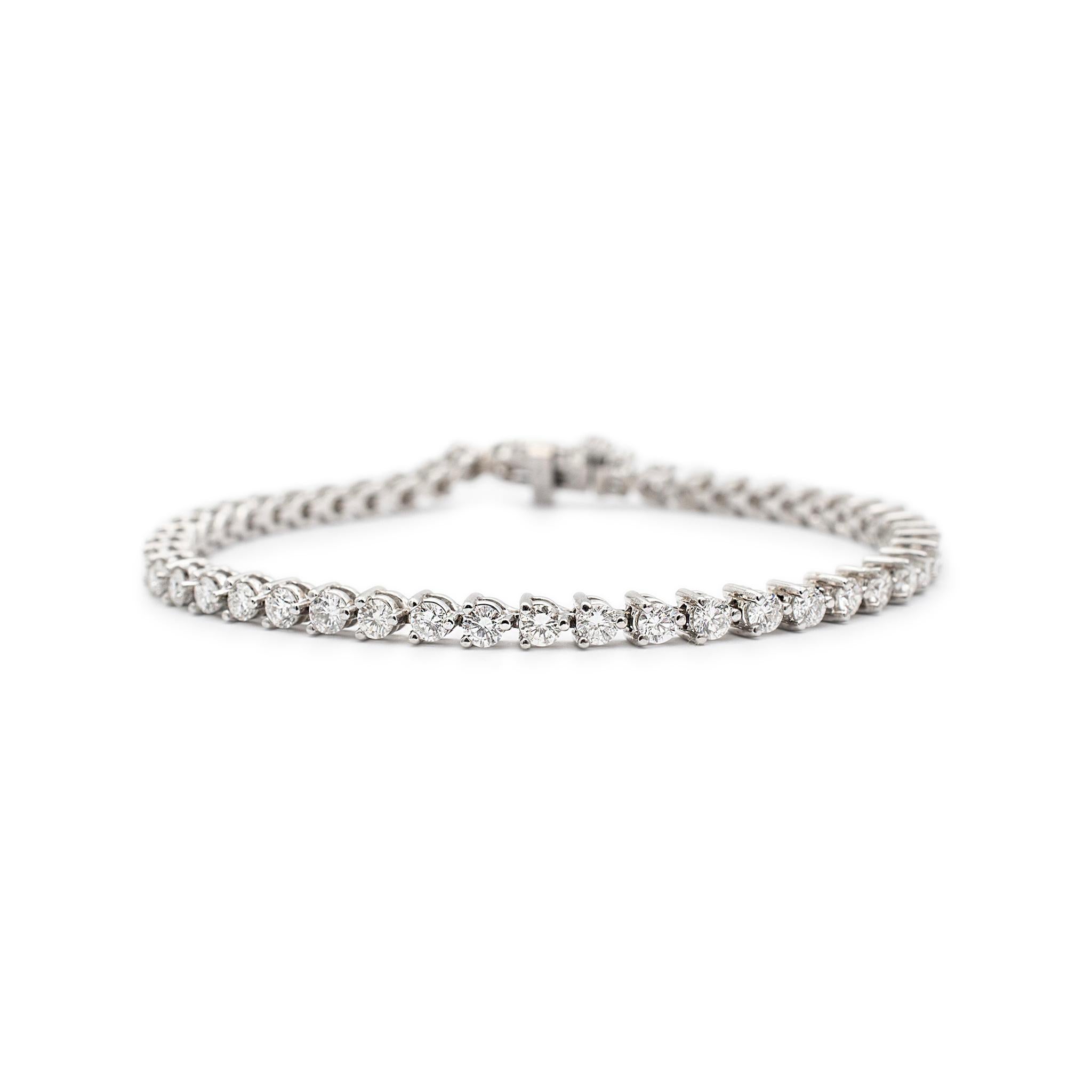 One lady's custom made polished 14K white gold, diamond tennis bracelet. The bracelet is 3.80mm thick and measures approximately 7.00 inches in length by 2.92mm in width and weighs a total of 9.82 grams. Engraved with 