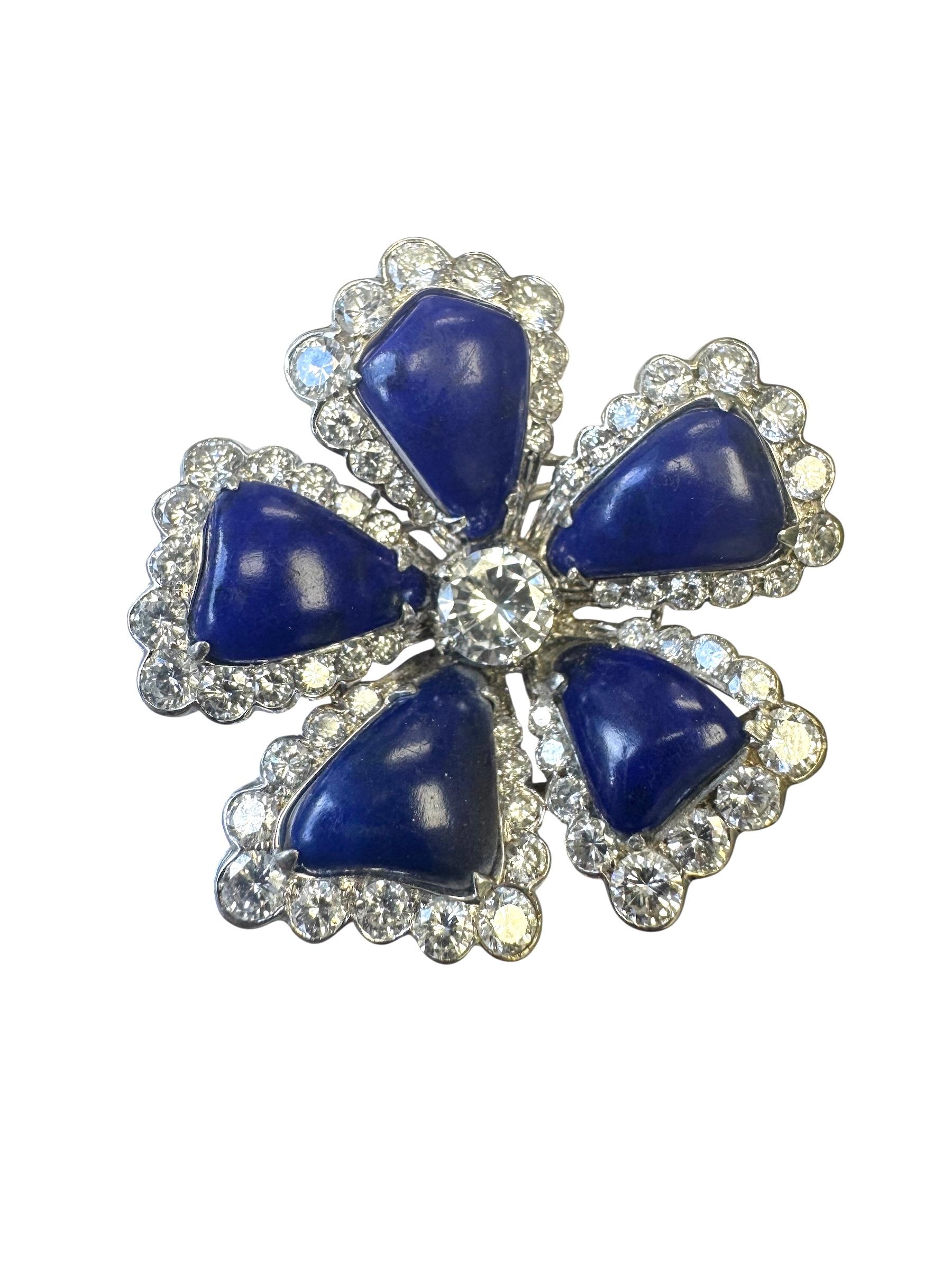 Cette broche en forme de fleur, réalisée en or blanc 14 carats, met en valeur cinq pétales de lapis-lazuli bleu vif. Chaque pétale est bordé d'un halo festonné de diamants ronds de taille brillant étincelants, soulignant la riche teinte du lapis. Au