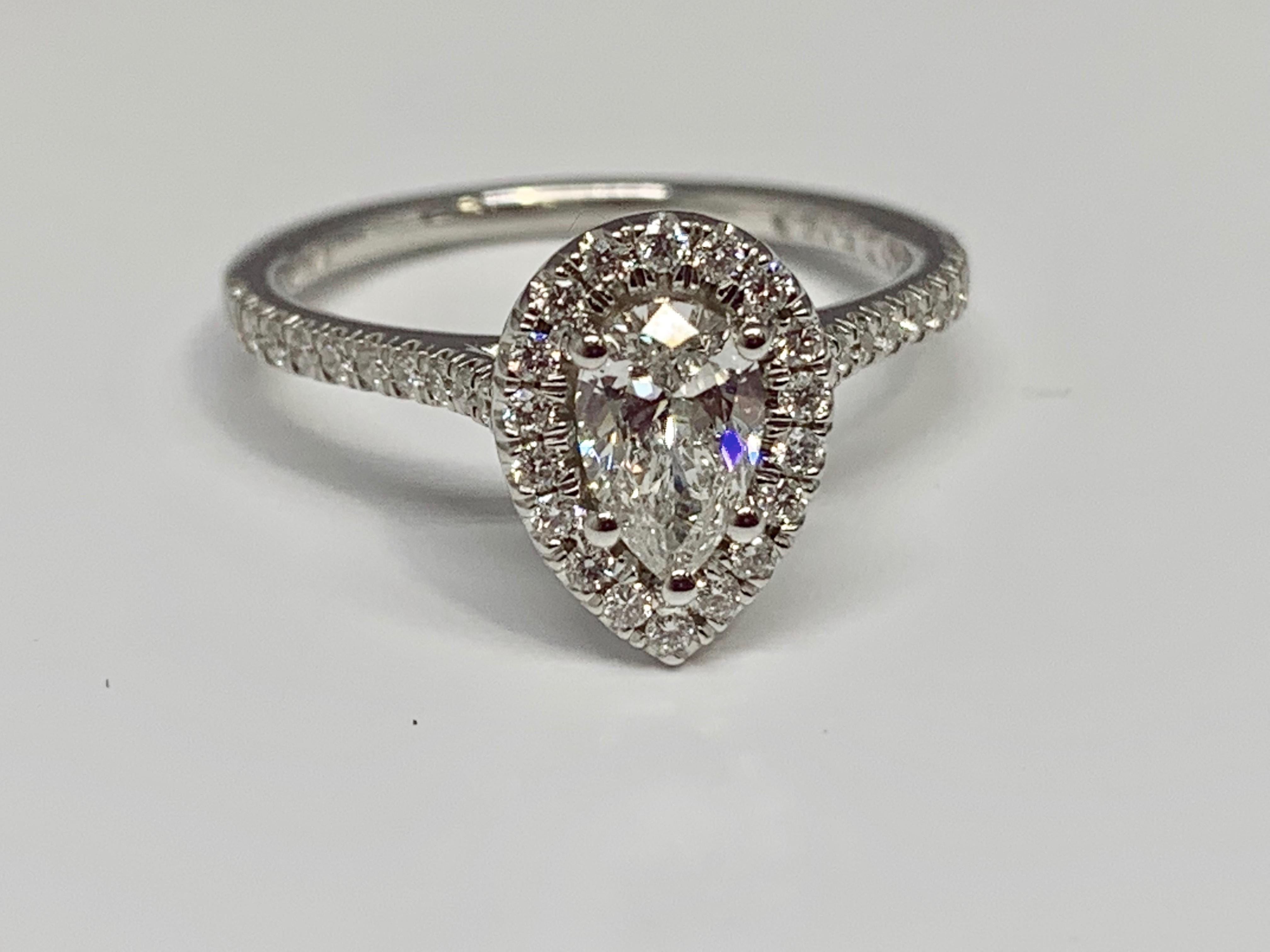 This classic halo style engagement ring from Martin Flyer features a 1/2 carat pear brilliant GIA center diamond with a color grade of G and a clarity grade of SI2. The micro pave diamond mounting is made of 14K white gold. This ring is currently a