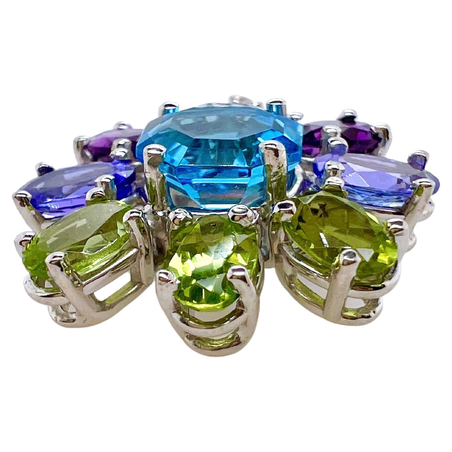 This beautiful, semi-precious pendant is arranged in a whimsical, floral pattern.  The peridots, amethysts, tanzanites, and blue topazes make up he colorful arrangement.  A perfect way to finish any outfit for a lighter, more playful