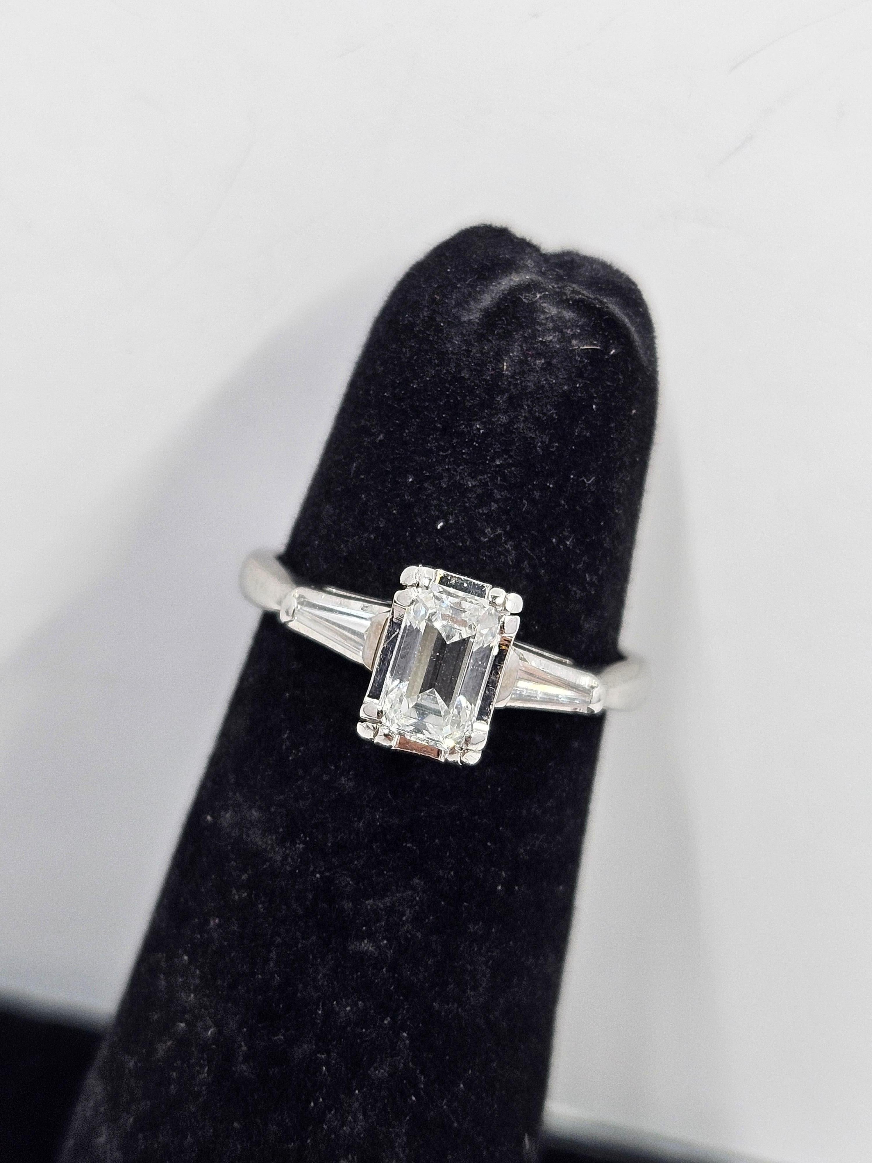Wunderschöner Verlobungsring aus 14-karätigem Weißgold mit einem natürlichen Diamanten im Smaragdschliff. Hauptstein .65ct. D Farbe VS2 flankiert von zwei .08ct. D Farbe VS spitz zulaufende Baguette-Diamanten.