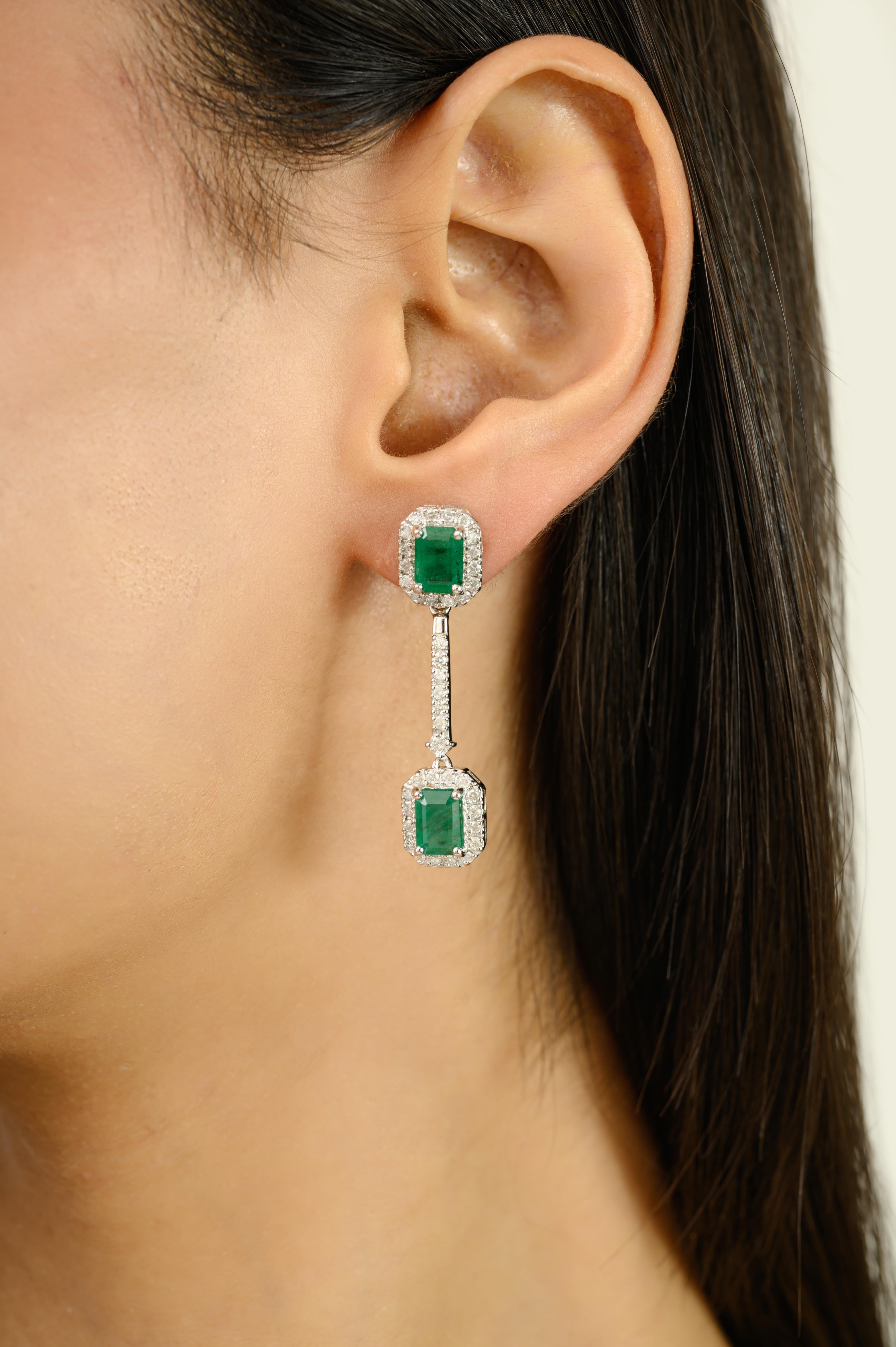 Exuding timeless elegance, these 14k White Gold Octagon Cut Emerald & Diamond Halo Dangle Earrings are crafted in 14k white gold. Each earring features two vibrant natural emeralds, weighing a total of 4.32 carats, celebrated for their rich green