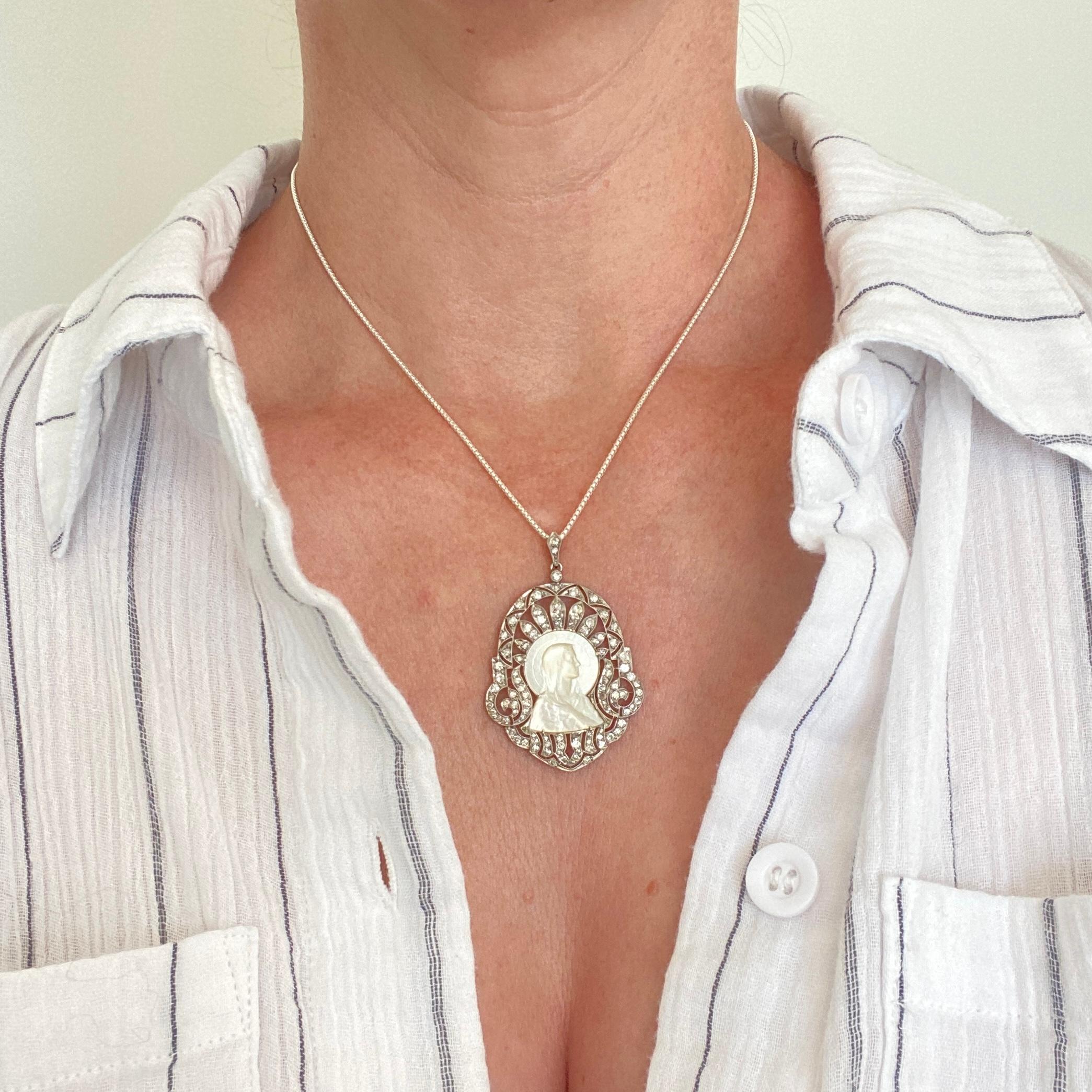 Colgante de oro blanco de 14 quilates de talla completa y talla antigua de diamantes madreperla, mide 1,3 pulgadas de ancho y 2 pulgadas de largo completo.  La Virgen tallada en nácar mide 0,9 pulg. x 0,6 pulg.  Diamantes redondos.  Un precioso