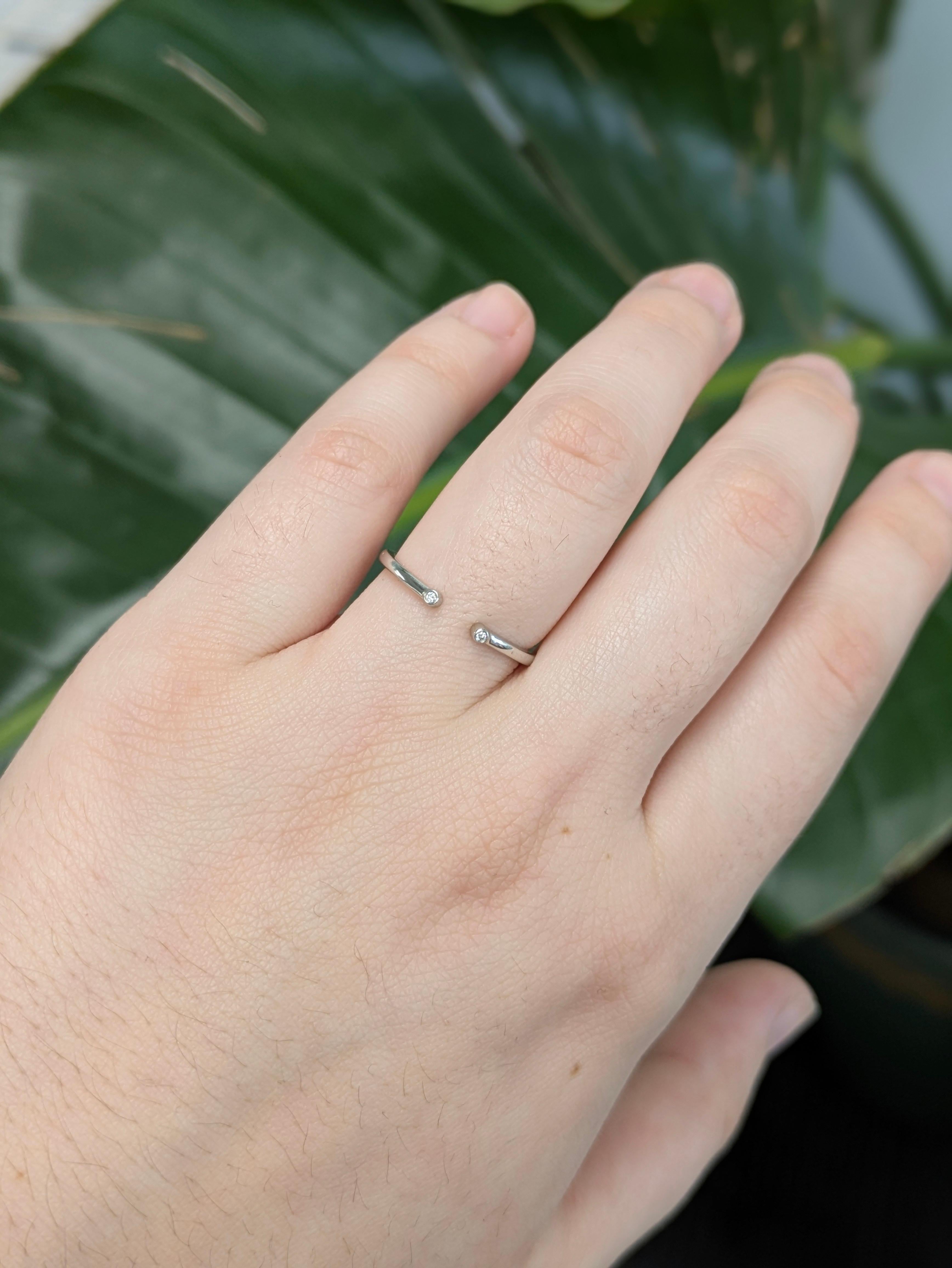Delicato ma resistente, questo anello in oro bianco massiccio 14k presenta due diamanti naturali incastonati che brillano alle estremità aperte. Il design pulito e aperto lo rende perfetto per essere impilato o indossato in modo minimalista. Un