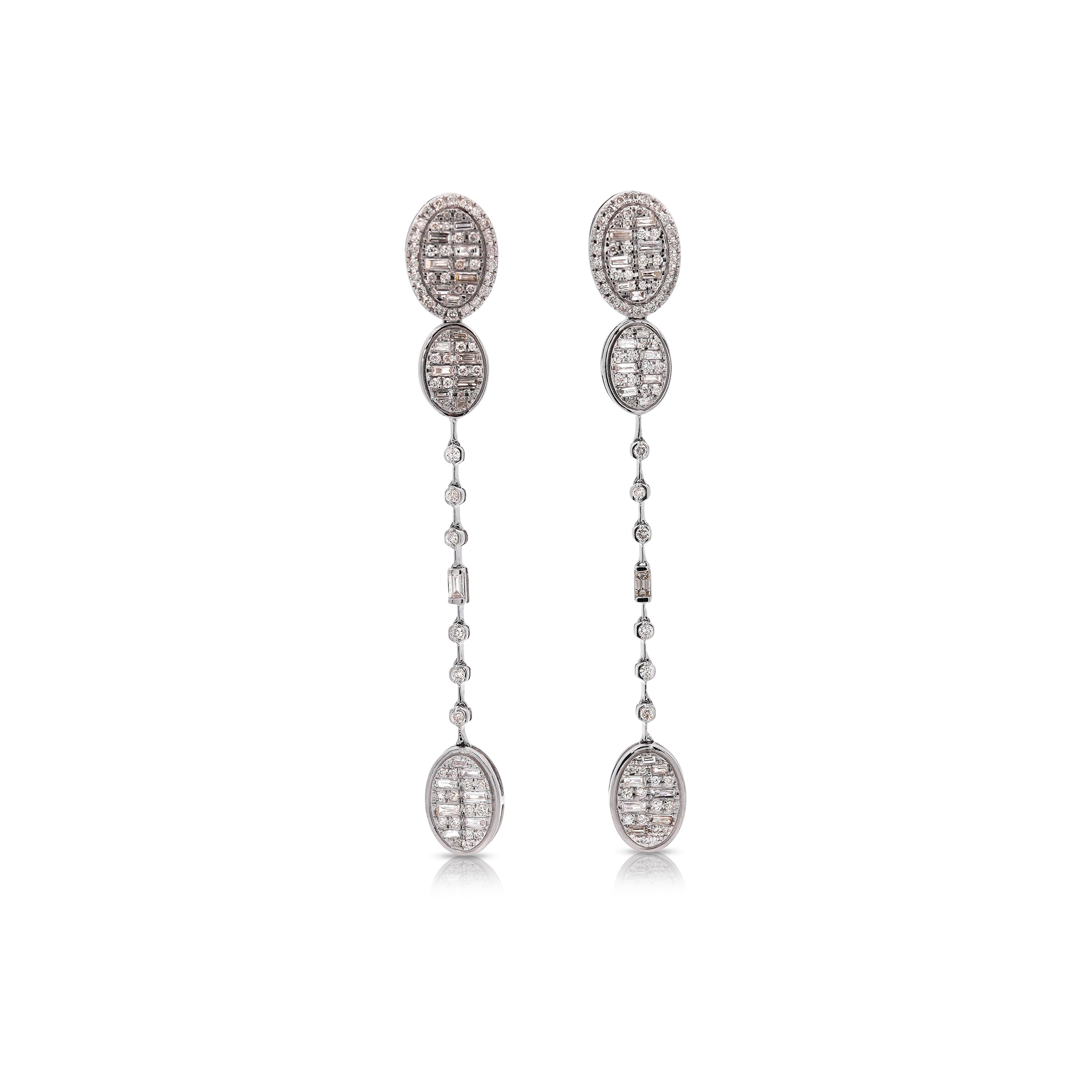 Questi orecchini di diamanti sono realizzati in oro bianco 14K. Hanno un design a goccia ovale e un totale di 1,04 carati. I diamanti hanno un taglio rotondo e a baguette e sono classificati come G-H e VS2-SI1. Gli orecchini presentano un