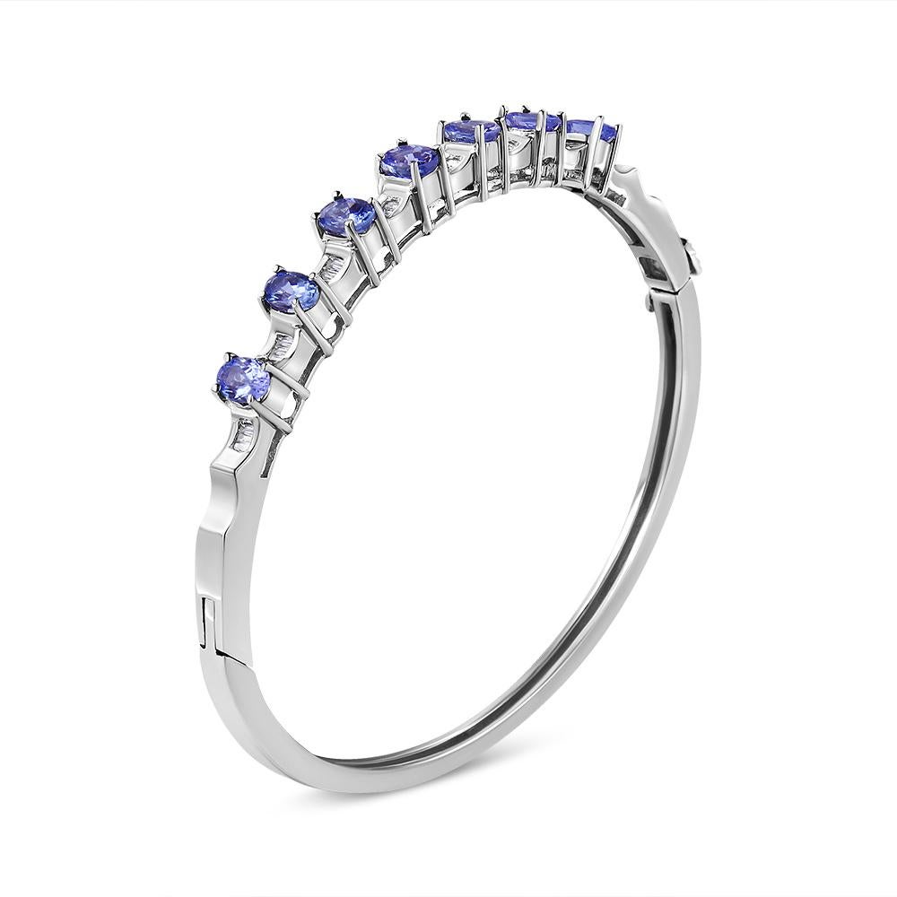 Wrap your wrist in the prettiest shade of blue. Our 14K White Gold bangle bracelet showcases 7 oval tanzanite stones measuring in at a whooping 5MM each. Diamond-accented sections highlight each lovely violet stone. The bangle has 24 natural,