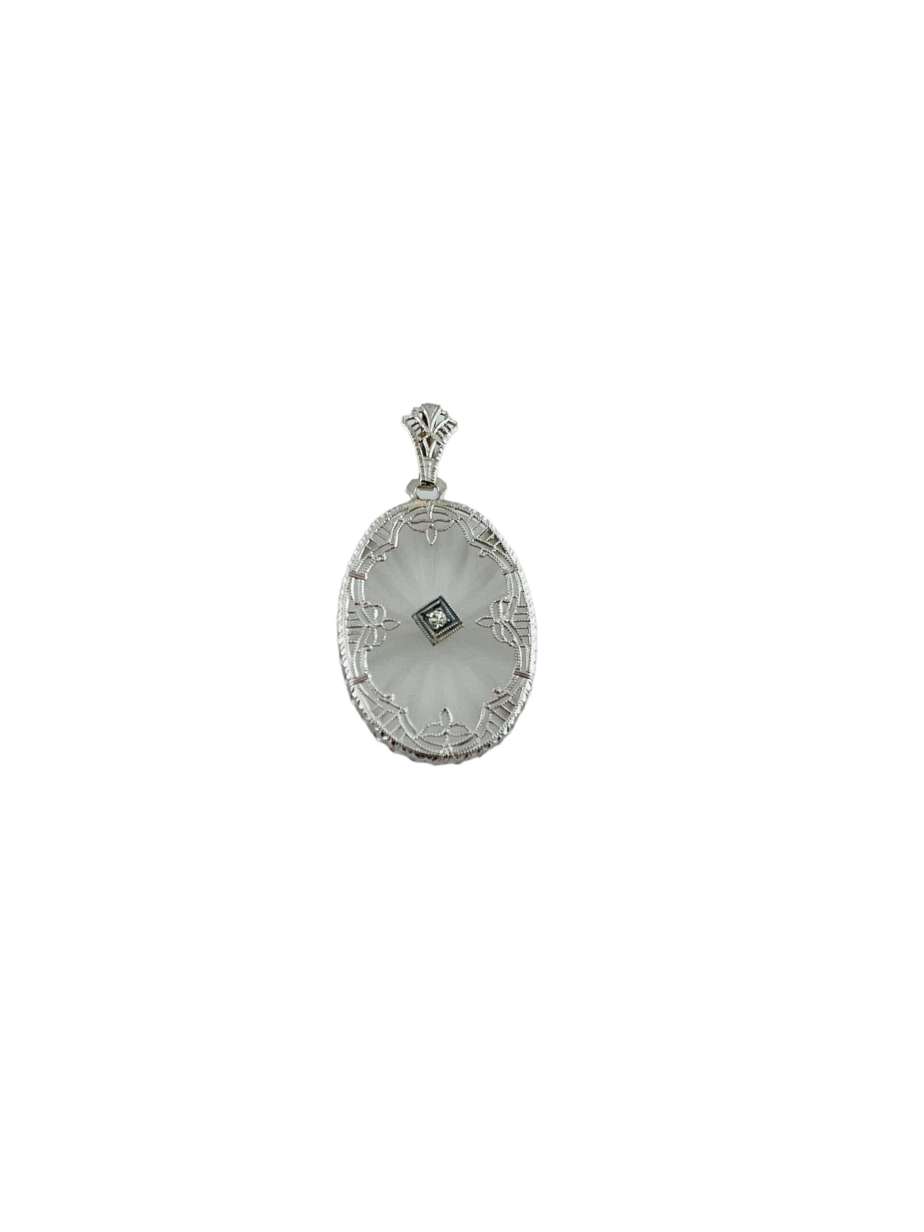 This beautiful oval pendant features camphor glass accented in a scrolling white gold frame.

Center of the pendant is decorated with a single cut diamond framed in white carat gold

The diamond weighs approx. .03 cts and is of SI1 clarity and K