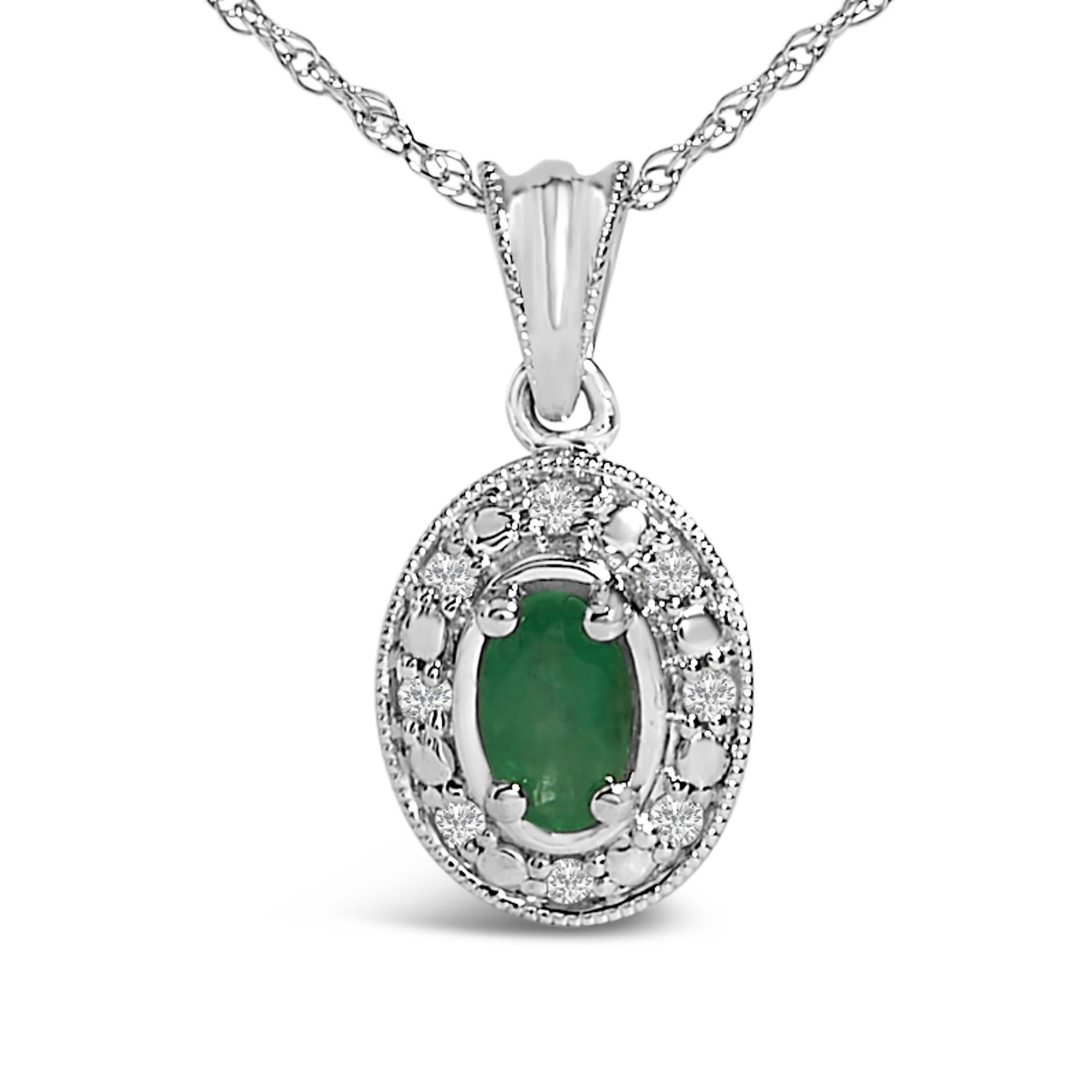 Ce collier pendentif en or blanc 14 carats est très élégant. Une émeraude verte ovale naturelle se trouve majestueusement au centre du collier. Cette pierre précieuse de 5x3 mm, rehaussée par un huilage traditionnel pour mettre en valeur ses teintes
