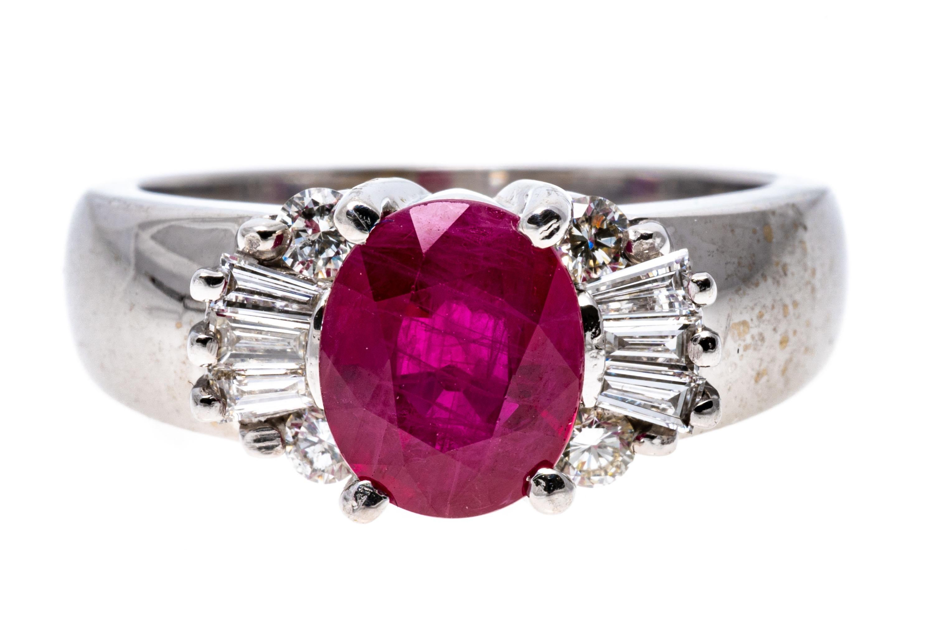 This beautiful white gold ring has a center oval faceted, pinkish red color ruby, approximately 1.83 CTS, prong set. The ruby is flanked by shoulders set with a fan of tapered baguette cut diamonds, approximately 0.12 TCW, which is capped above and
