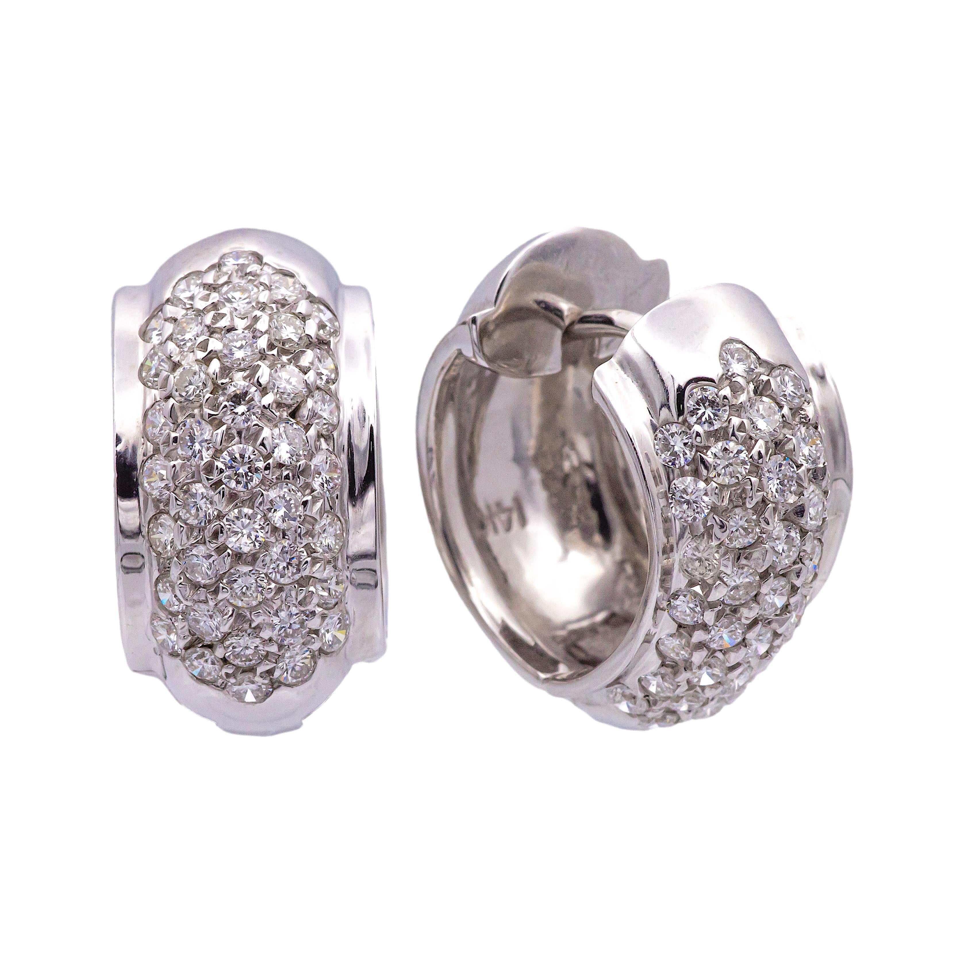 Pair of pave diamond huggie earrings finely crafted in 14K white gold featuring an array of sparkling pave set round brilliant cut diamonds weighing a total of approximately 1.20 carats total weight. Earrings have a hinge closure mechanism and
